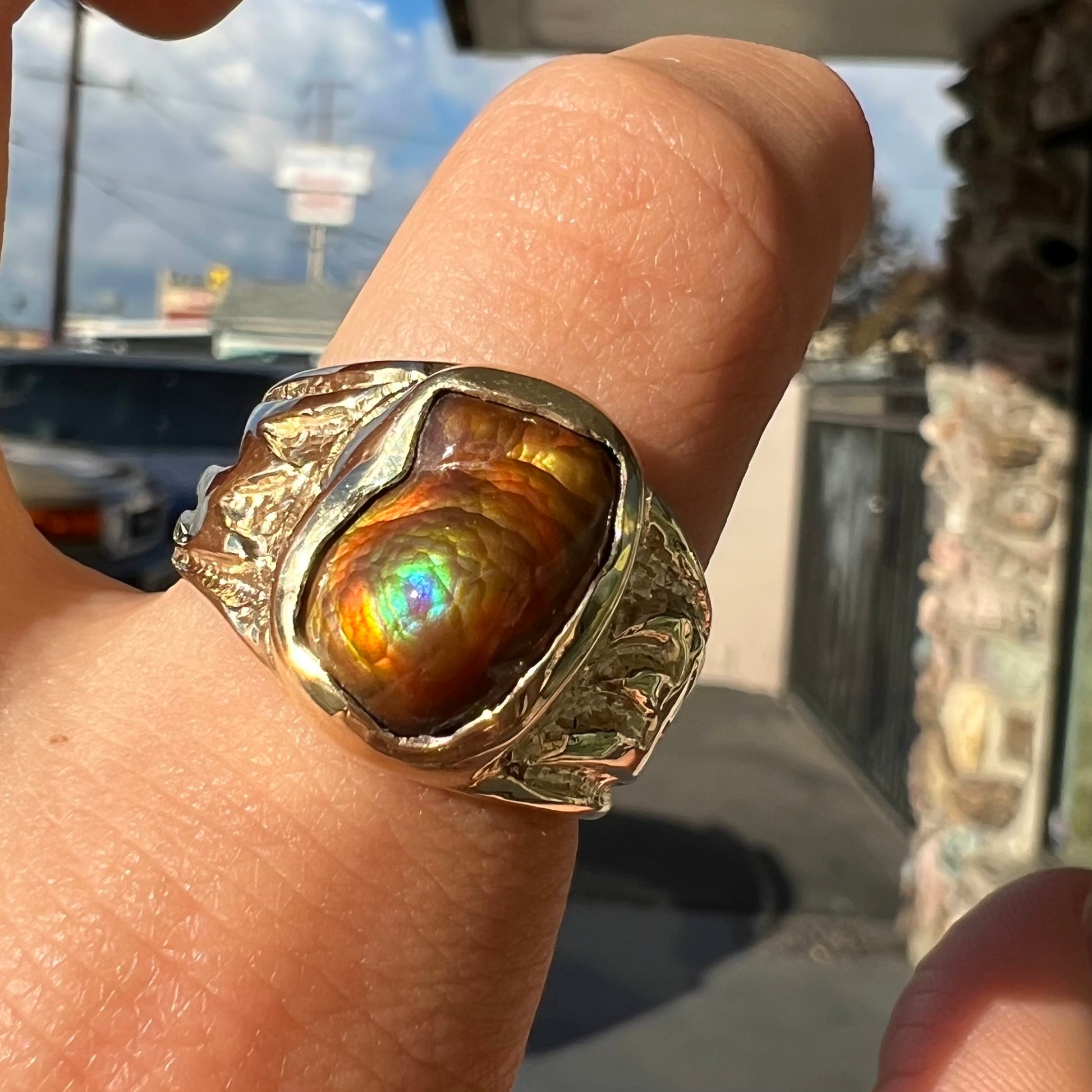 A man's yellow gold solitaire ring set with a freeform shaped Mexican fire agate stone.  The stone has a purple bull's eye pattern.