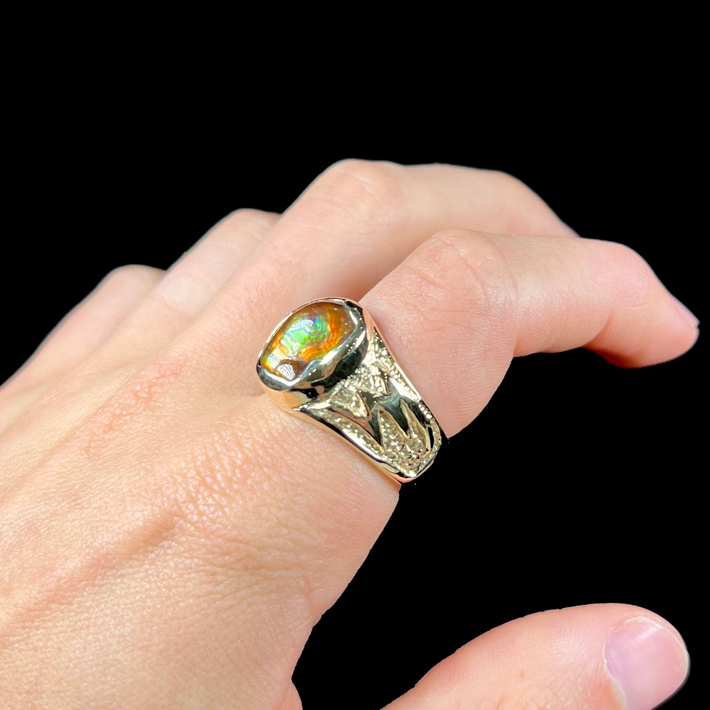A man's yellow gold solitaire ring set with a freeform shaped Mexican fire agate stone.  The stone has a purple bull's eye pattern.
