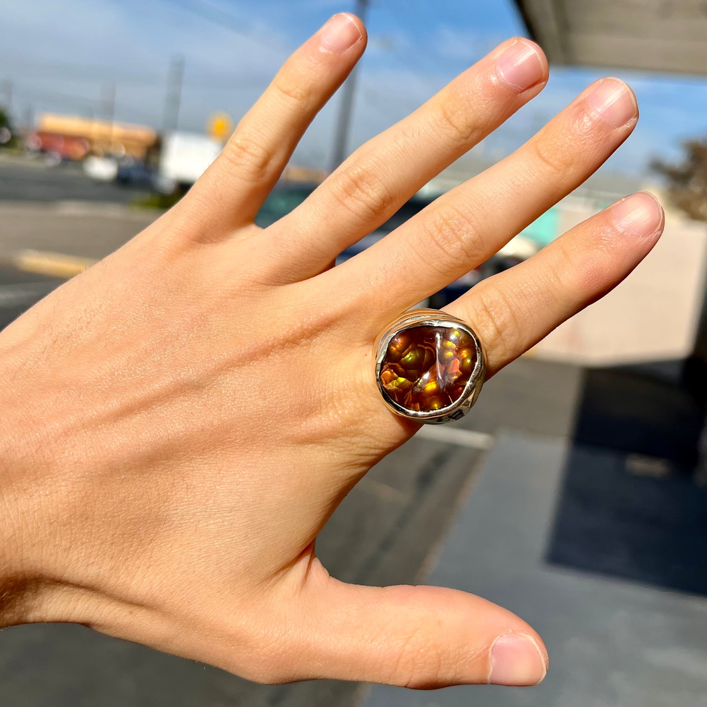 A men's heavy yellow gold ring set with a Mexican fire agate stone and three round brilliant cut diamond accents.