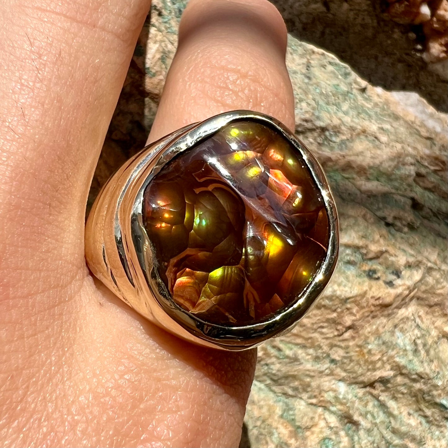 A men's heavy yellow gold ring set with a Mexican fire agate stone and three round brilliant cut diamond accents.