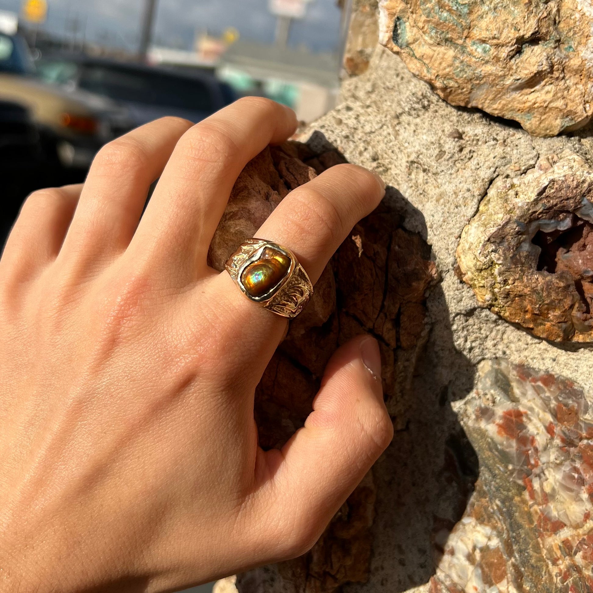 A man's yellow gold solitaire ring set with a freeform shaped Mexican fire agate stone.  The stone has a purple bull's eye pattern.