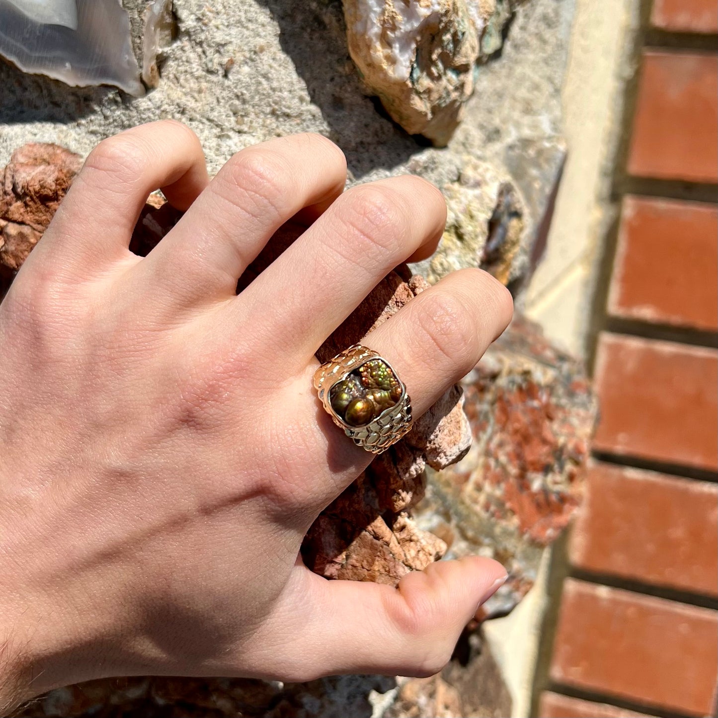 A men's yellow gold, nugget style ring set with a bubbly, California fire agate stone.