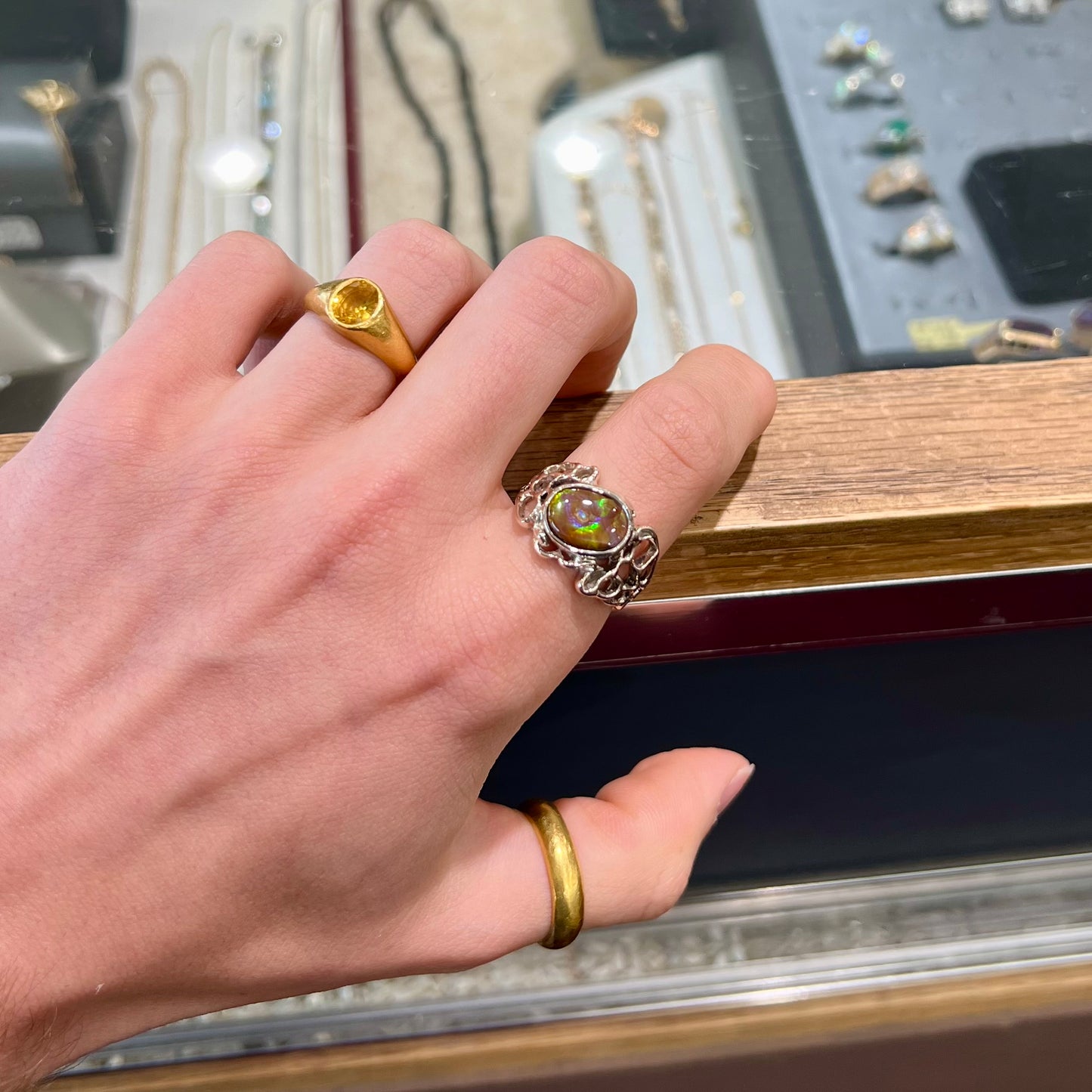 An organic-style white gold men's ring, bezel set with an oval cut Mexican fire agate stone.  The stone is green and purple.