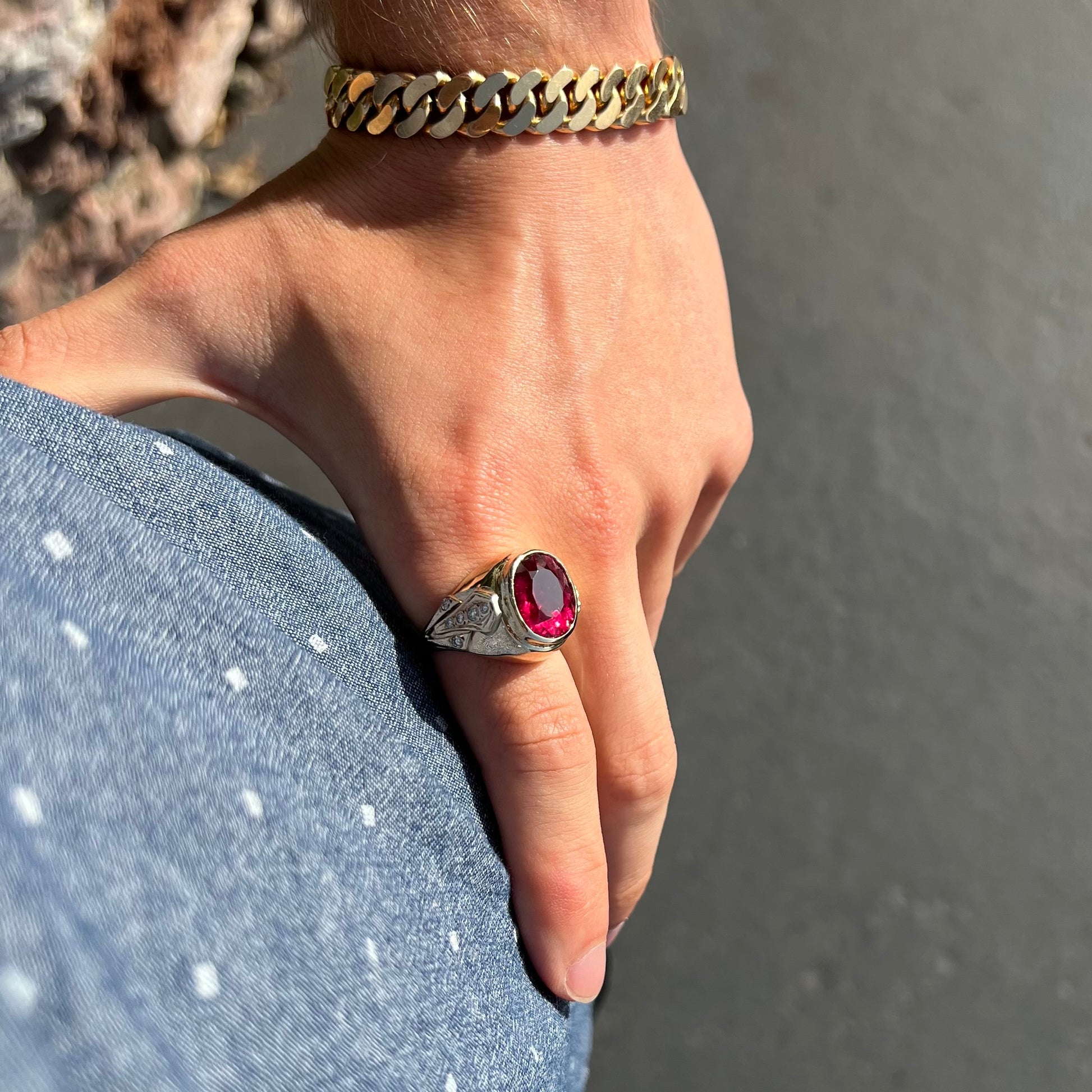 A men's yellow gold ring set with an oval cut rubellite tourmaline with diamond accents.