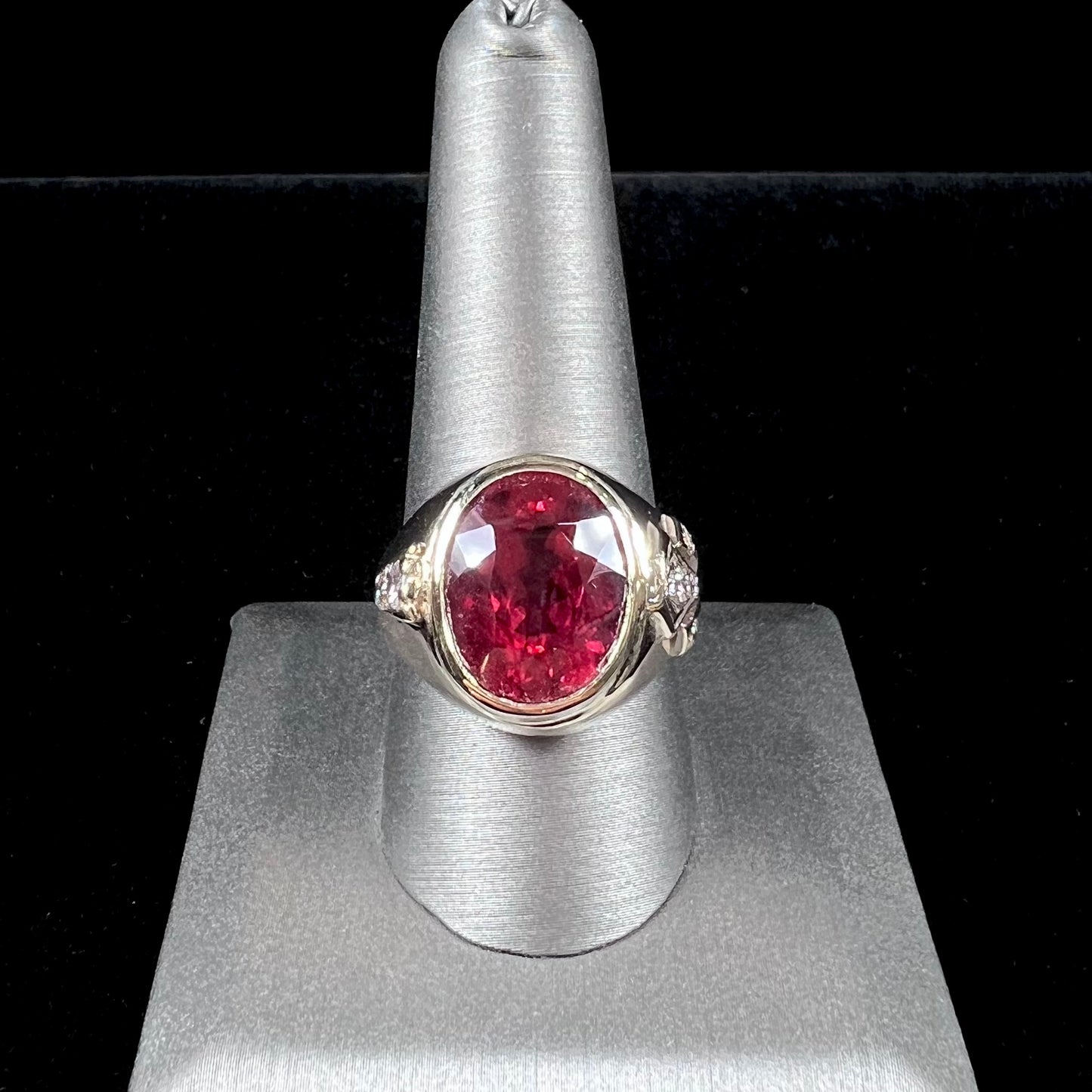 A men's yellow gold ring set with an oval cut rubellite tourmaline with diamond accents.