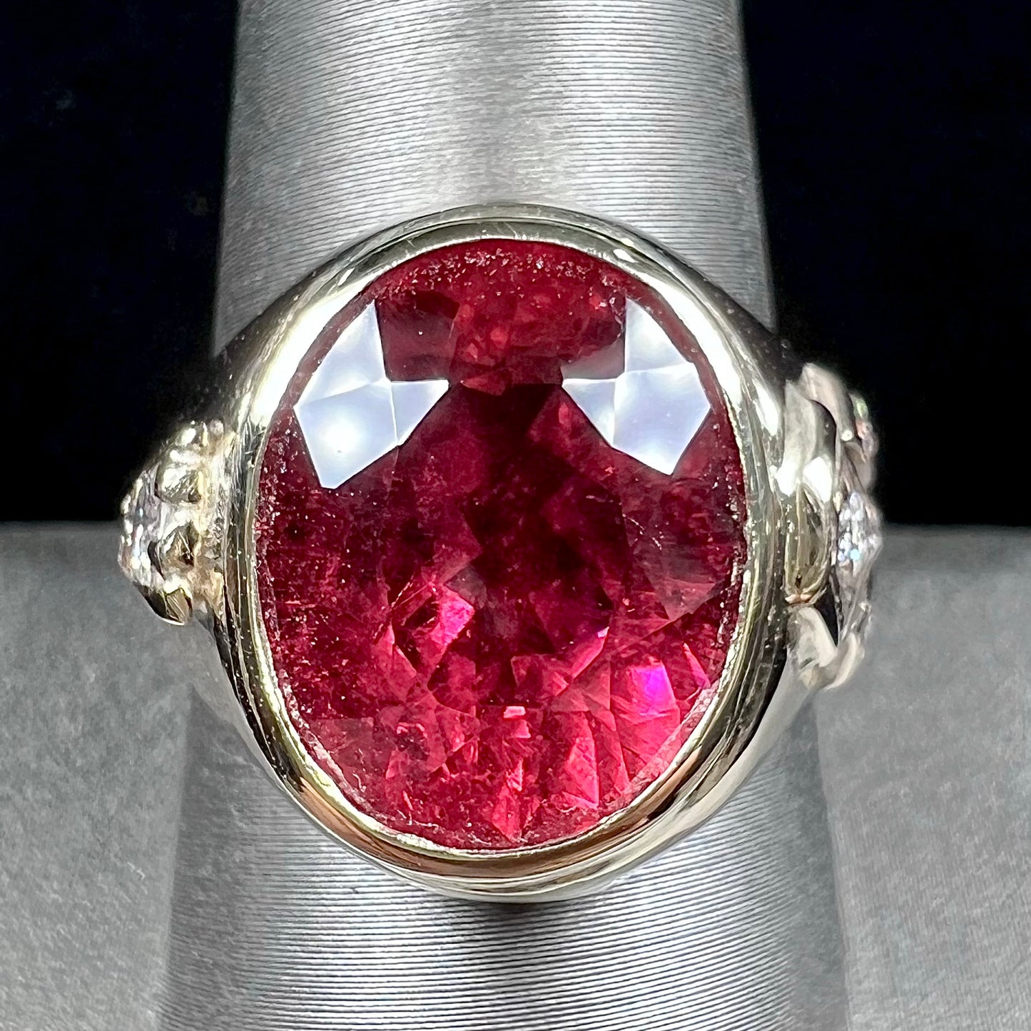 A men's yellow gold ring set with an oval cut rubellite tourmaline with diamond accents.