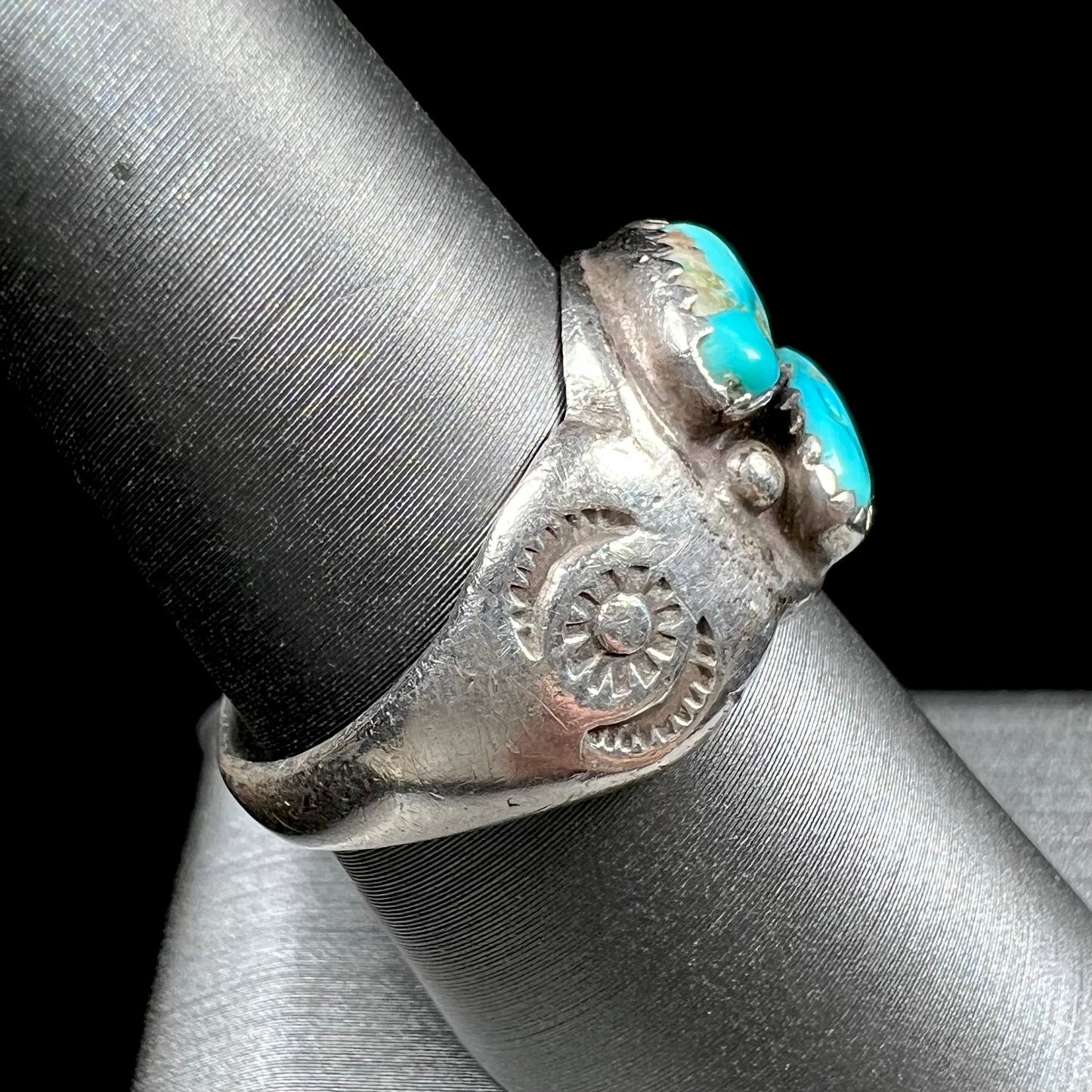 A unisex sterling silver ring bezel set with two Pilot Mountain turquoise stones.  The ring is stamped with sun patterns.