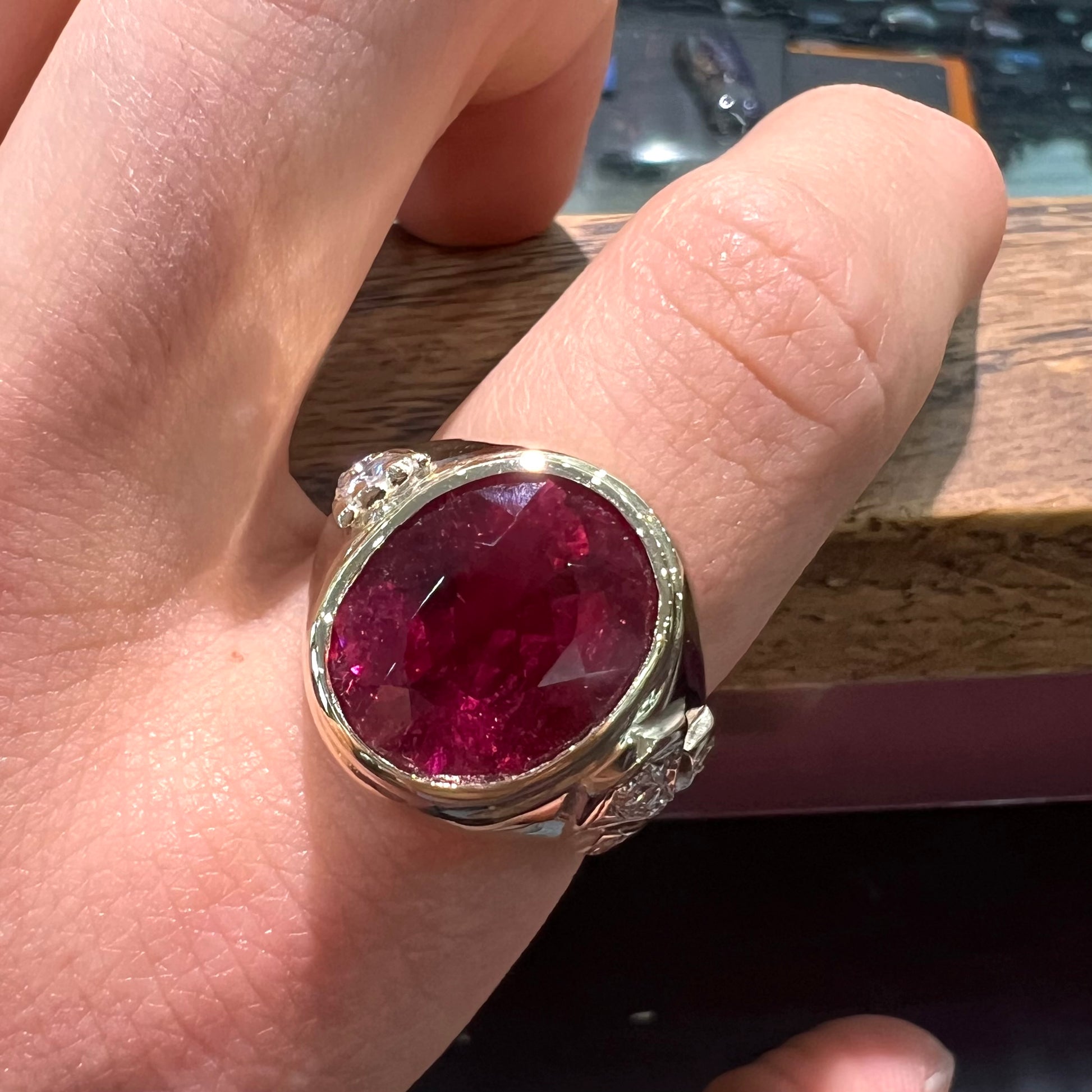 A men's yellow gold ring set with an oval cut rubellite tourmaline with diamond accents.