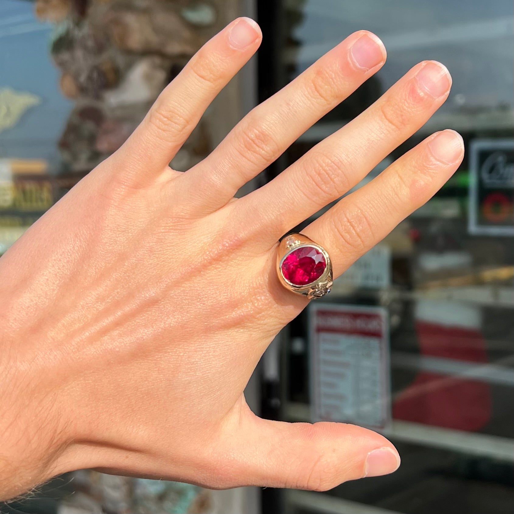 A men's yellow gold ring set with an oval cut rubellite tourmaline with diamond accents.