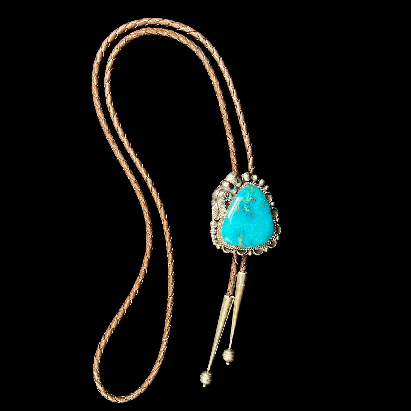 A men's sterling silver, Navajo style bolo tie set with a Pilot Mountain turquoise stone.  The rope is brown leather.