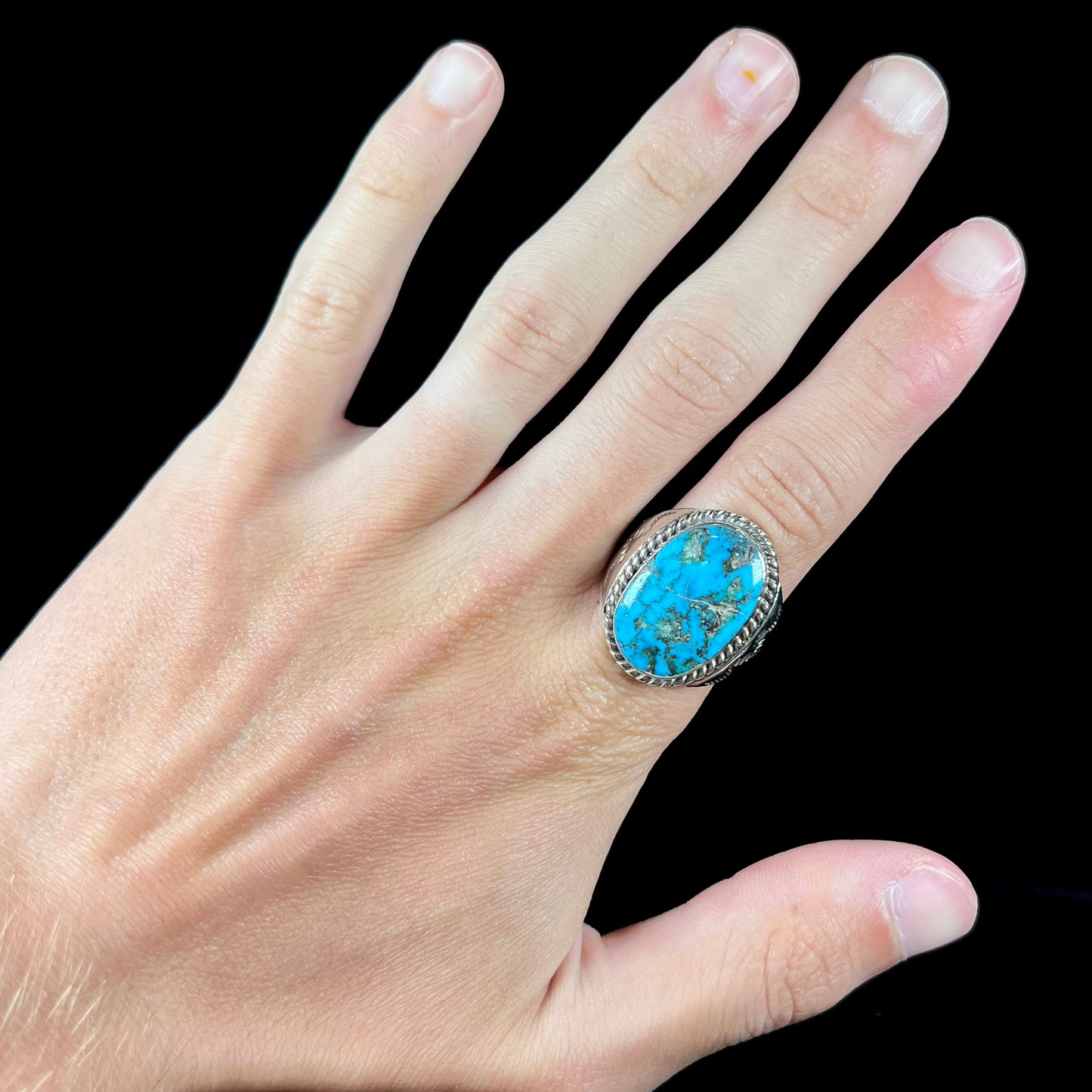 A men's sterling silver Morenci turquoise solitaire ring. The ring has a Southwest Navajo style stamp pattern.
