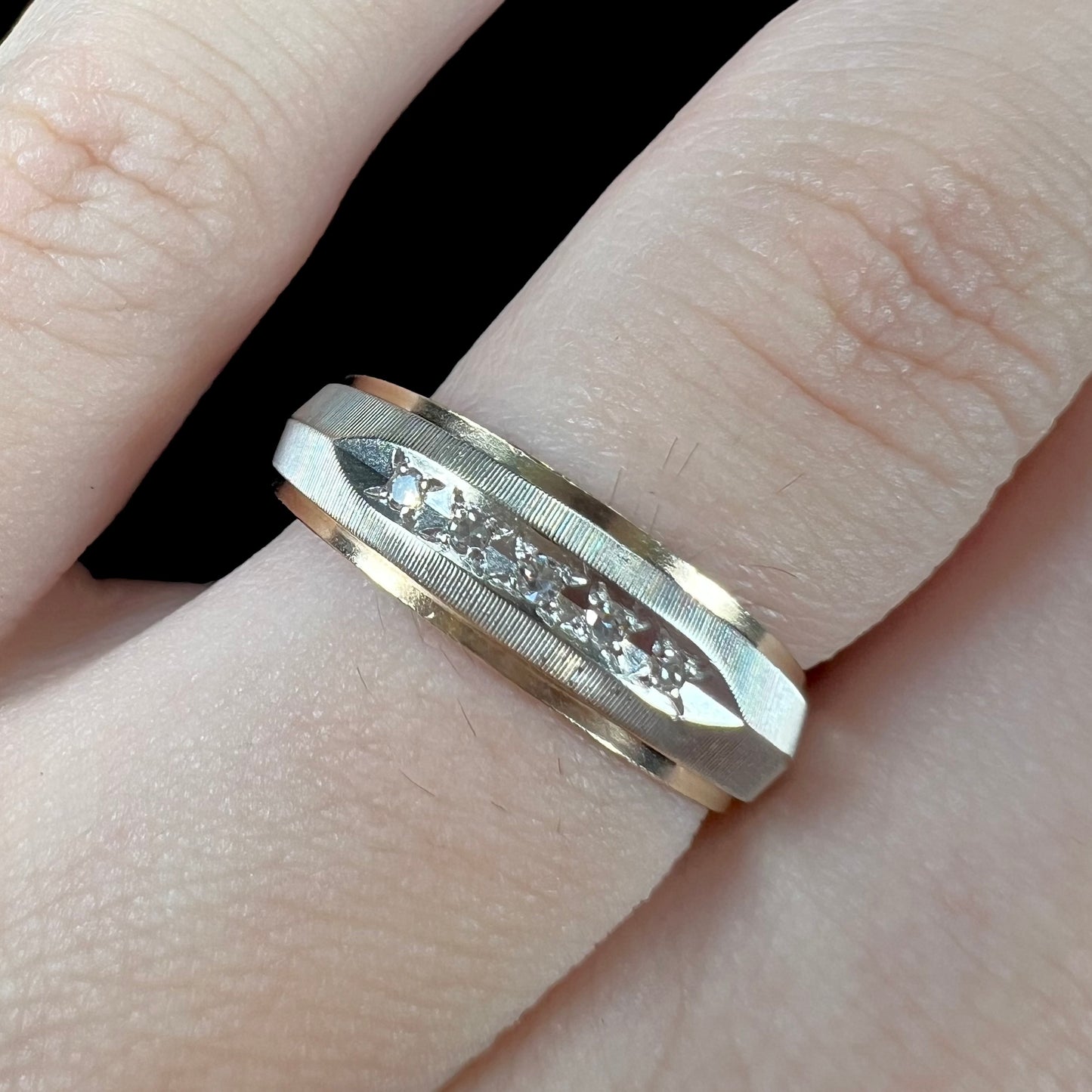 A unisex, two-tone white and yellow gold diamond wedding band. The white gold is textured.