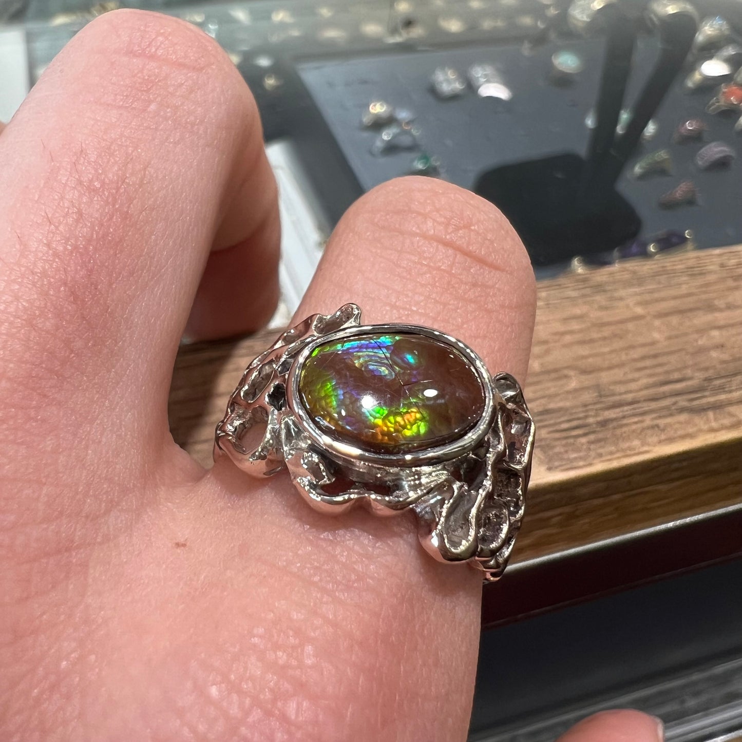 An organic-style white gold men's ring, bezel set with an oval cut Mexican fire agate stone.  The stone is green and purple.