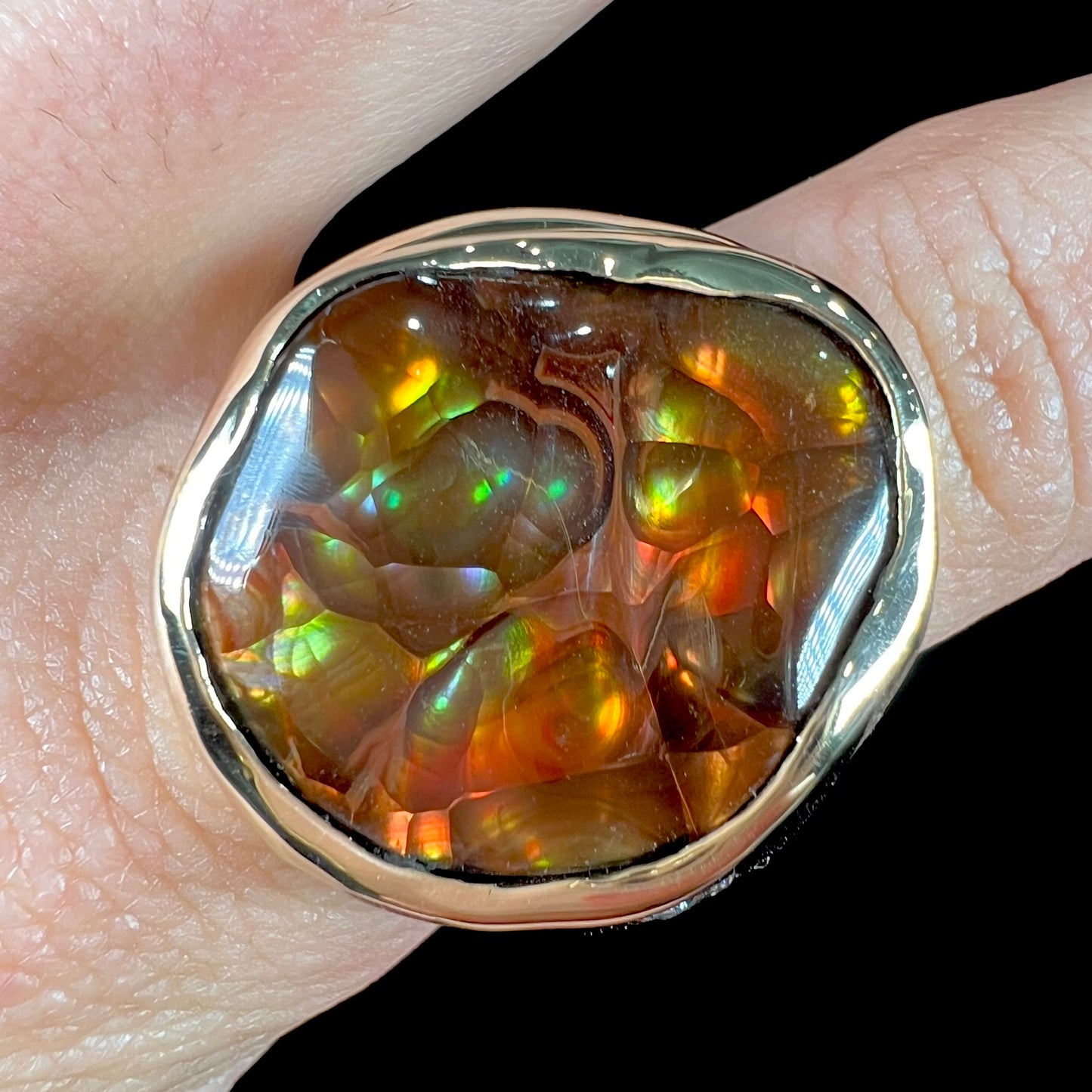 A men's heavy yellow gold ring set with a Mexican fire agate stone and three round brilliant cut diamond accents.