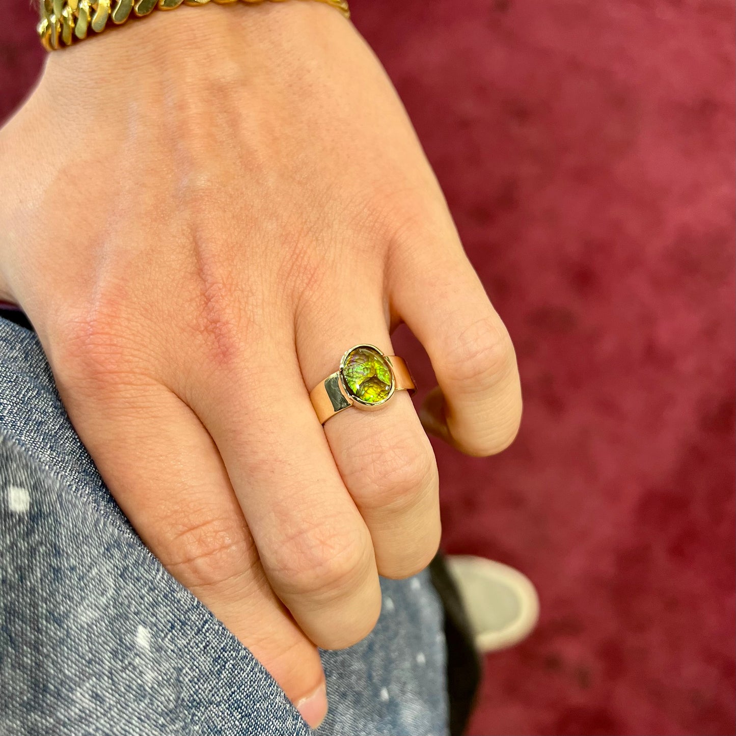 A unisex Mexican fire agate solitaire ring set in yellow gold. The stone is predominantly green and purple.