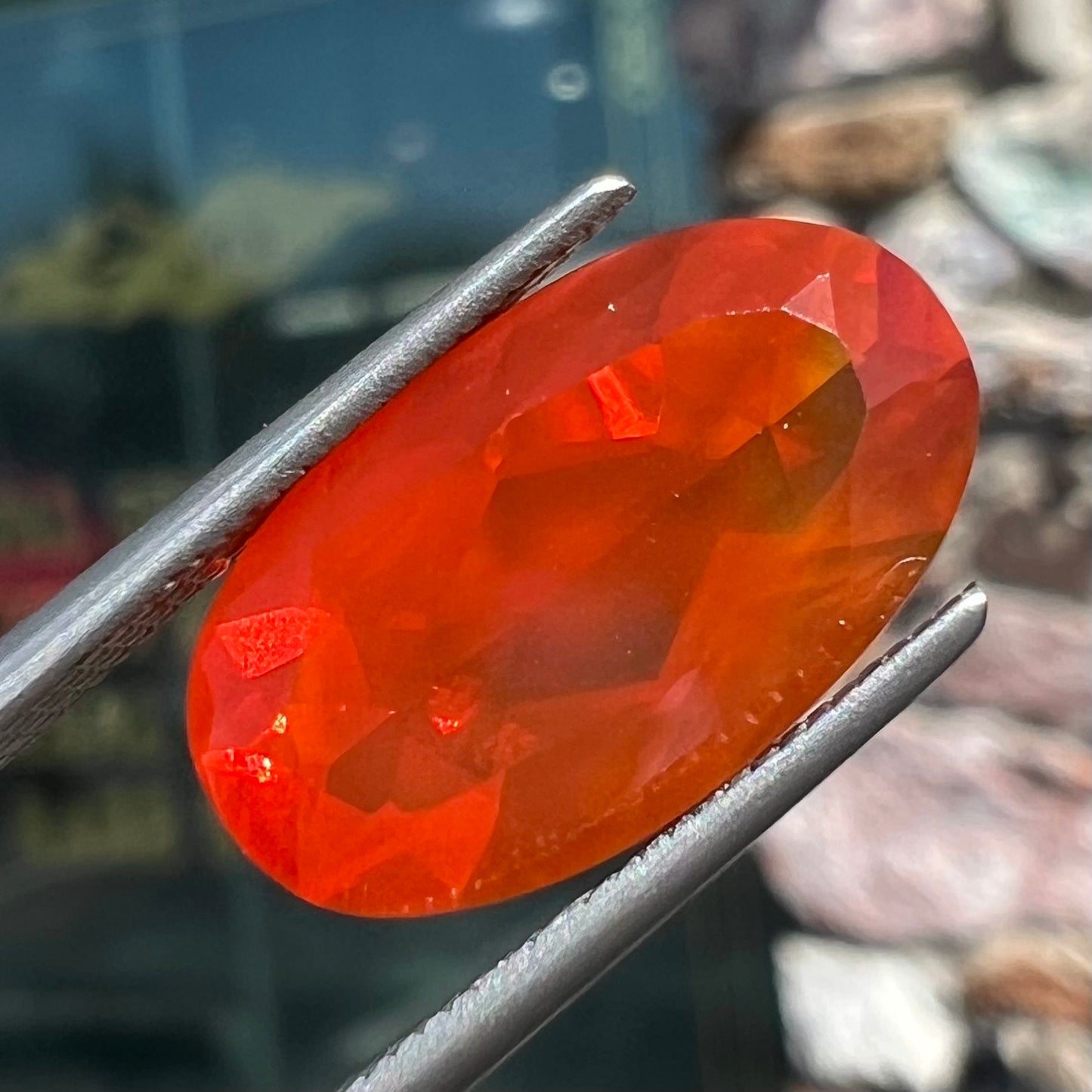 A loose, faceted oval cut Mexican fire opal stone. The stone is a bright orange color.