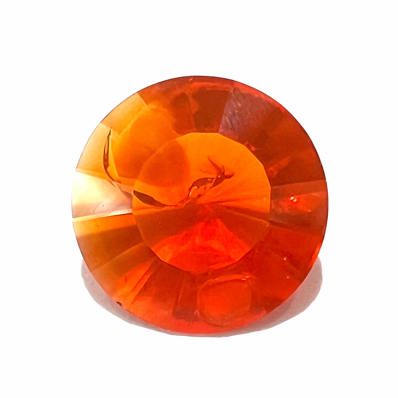 A faceted round cut natural fire opal from Mexico. The stone is a bright orange color.