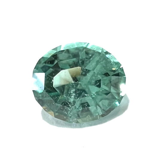 A loose, faceted modified oval cut mint green tourmaline gemstone.
