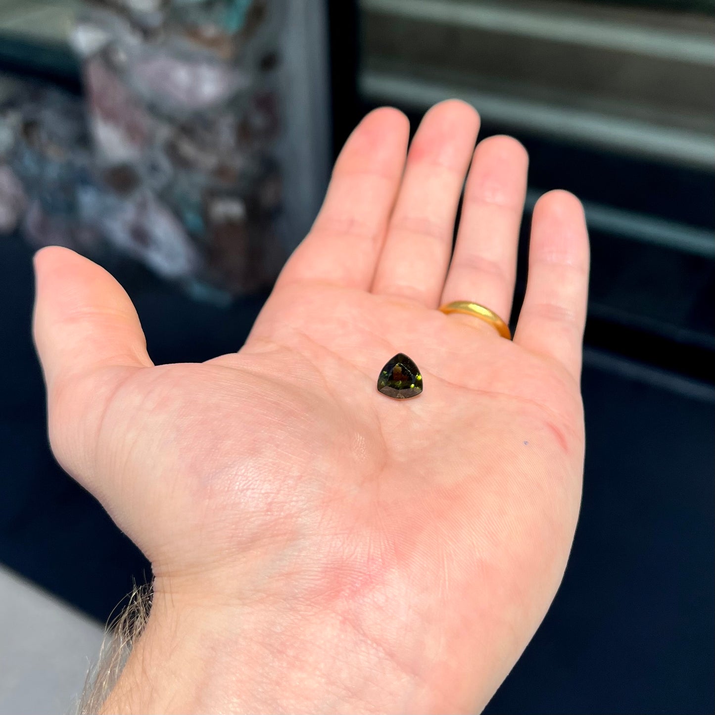 A natural, trillion cut moldavite gemstone.