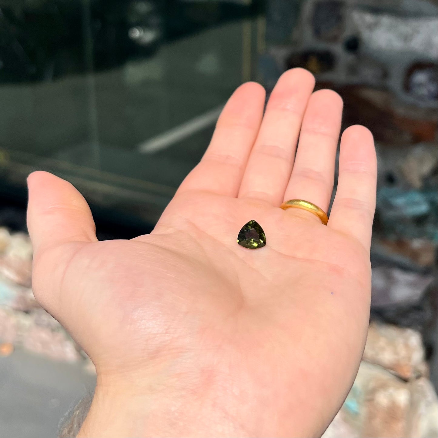 A trillion cut natural moldavite gemstone. The stone shows inclusions.