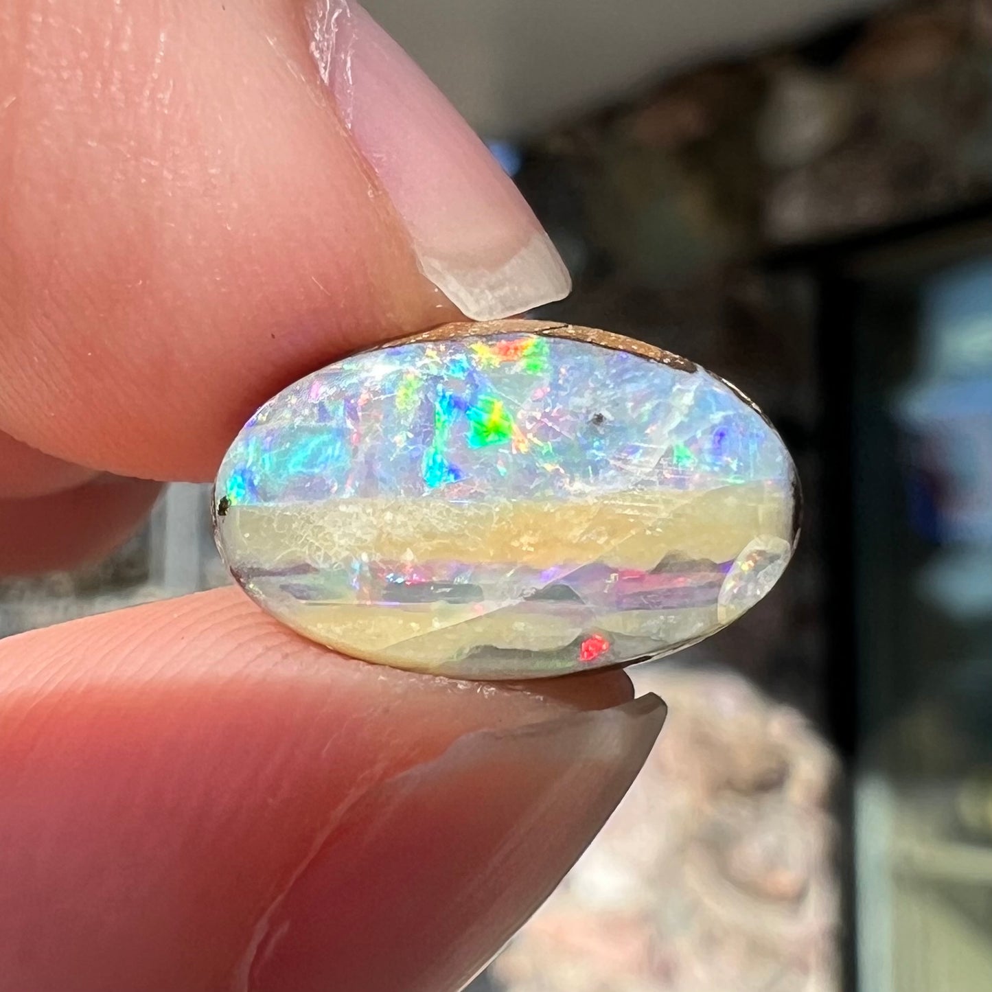 An oval cabochon cut boulder opal from Quilpie, Australia. The opal has multicolor color play.
