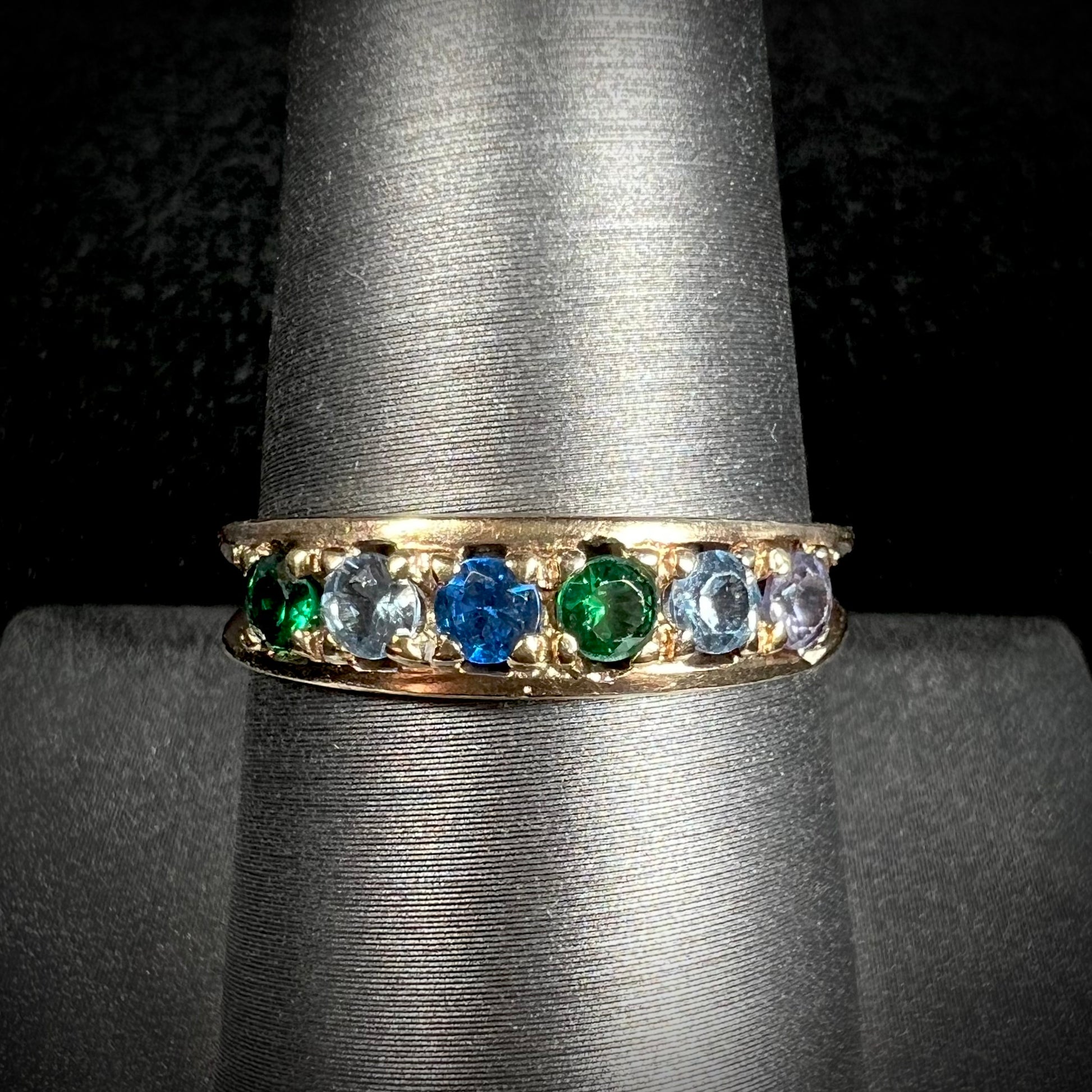 A ladies' yellow gold band set with green, dark blue, light blue, and light purple stones.