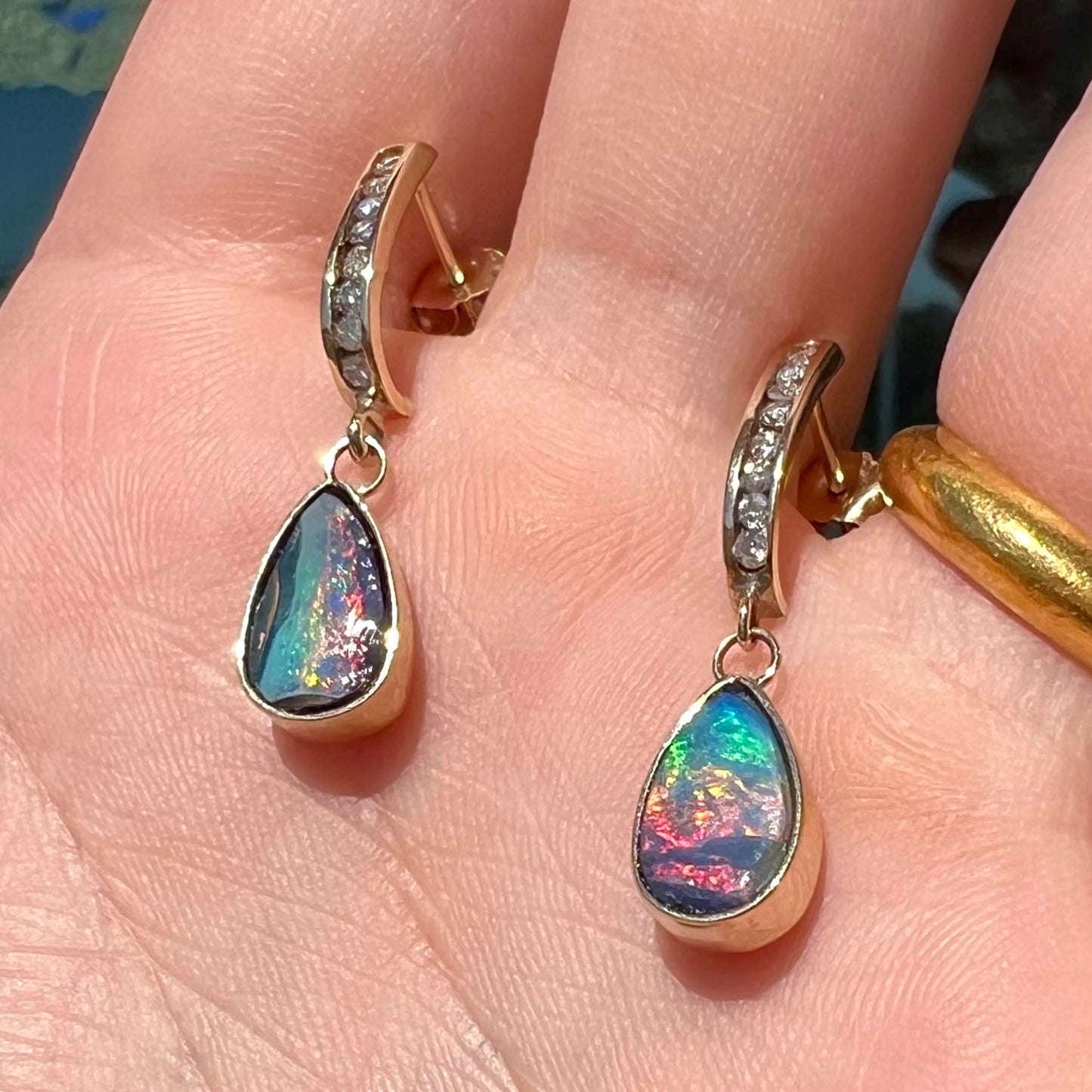 A pair of yellow gold dangle earrings set with natural pear shaped boulder opals and diamonds.
