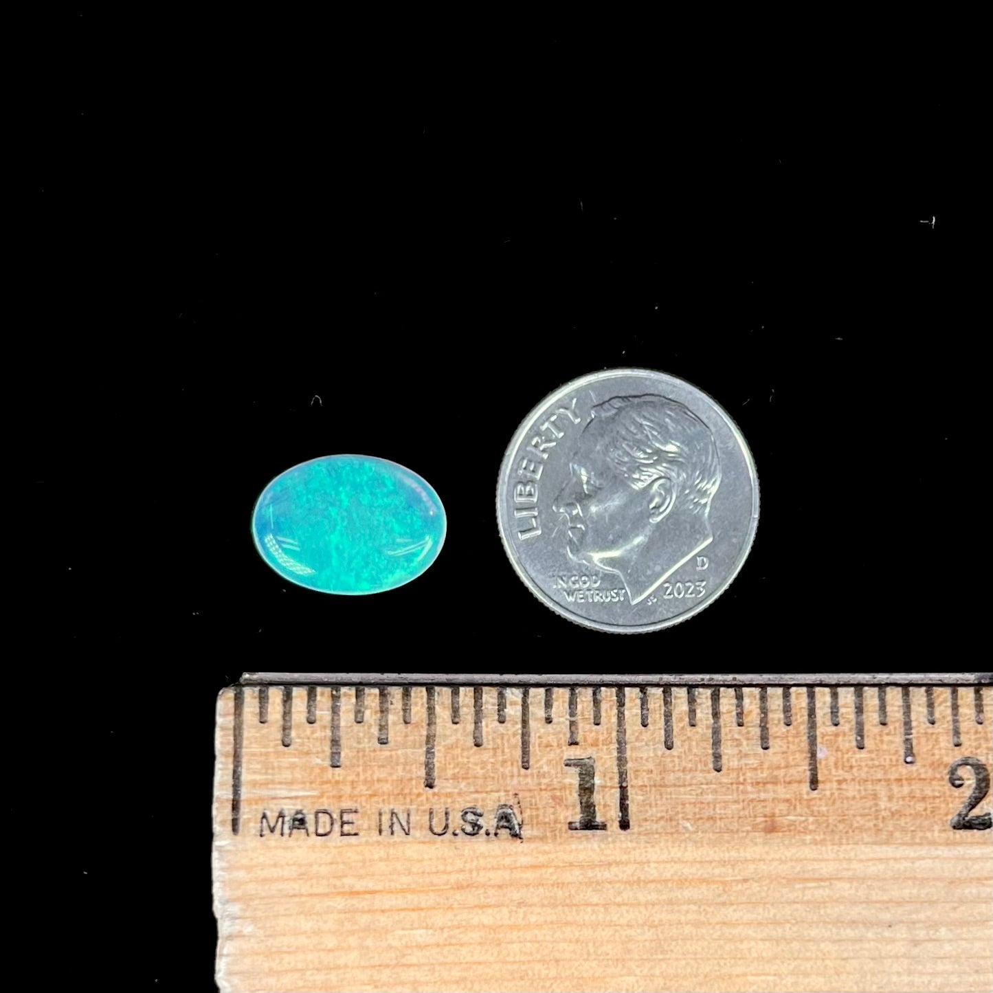 A loose, oval cabochon cut crystal opal from Coober Pedy, Australia. The opal has green and blue colors.