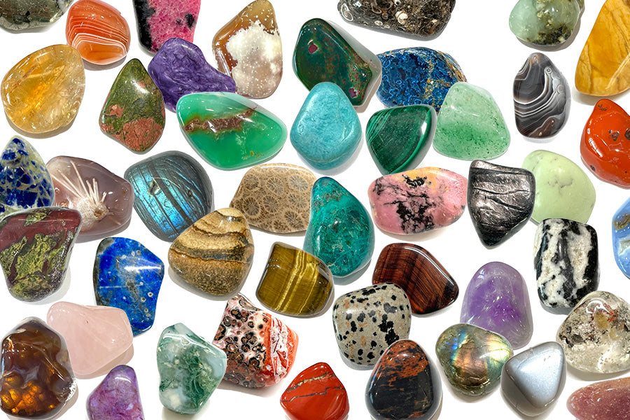 A collection of rare tumbled stones grouped together to display a rainbow of mineral colors.