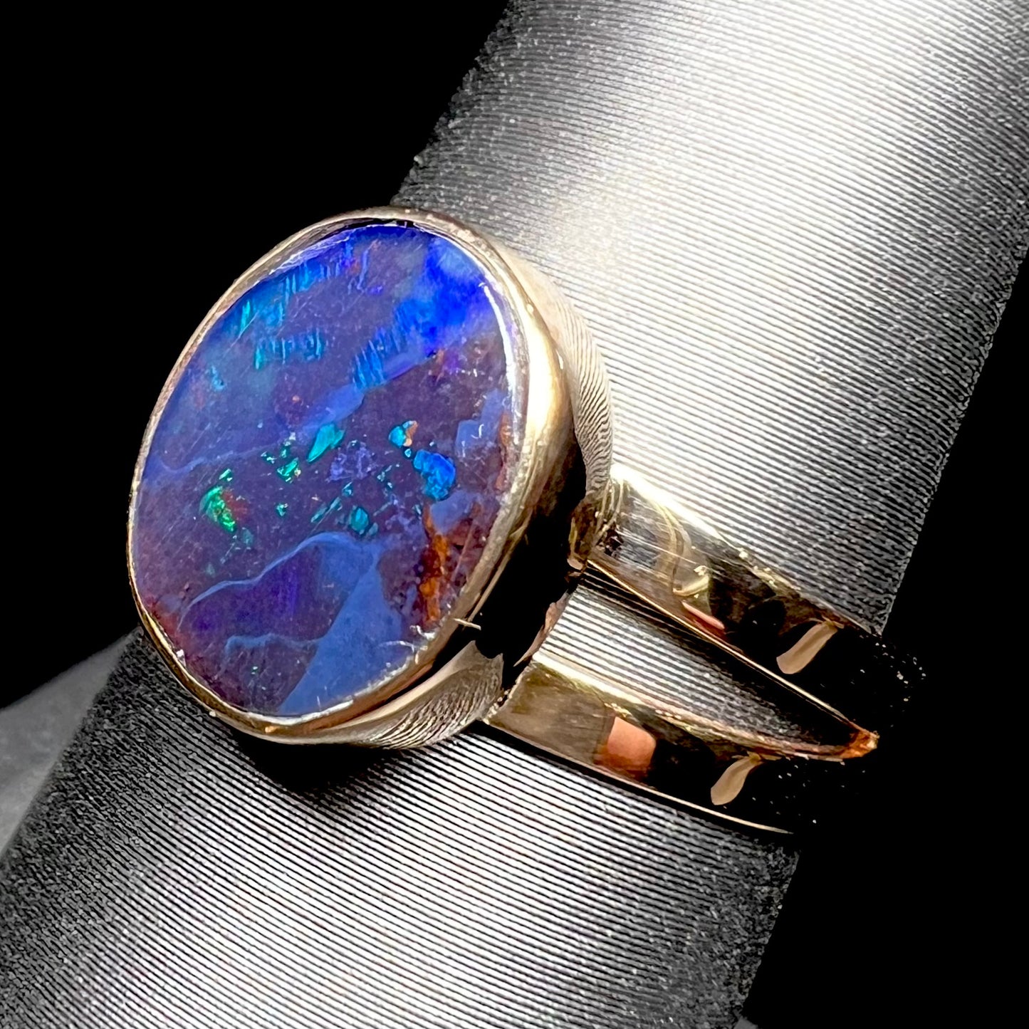 A ladies' split shank natural, Lightning Ridge, Australian black opal solitaire ring in yellow gold.