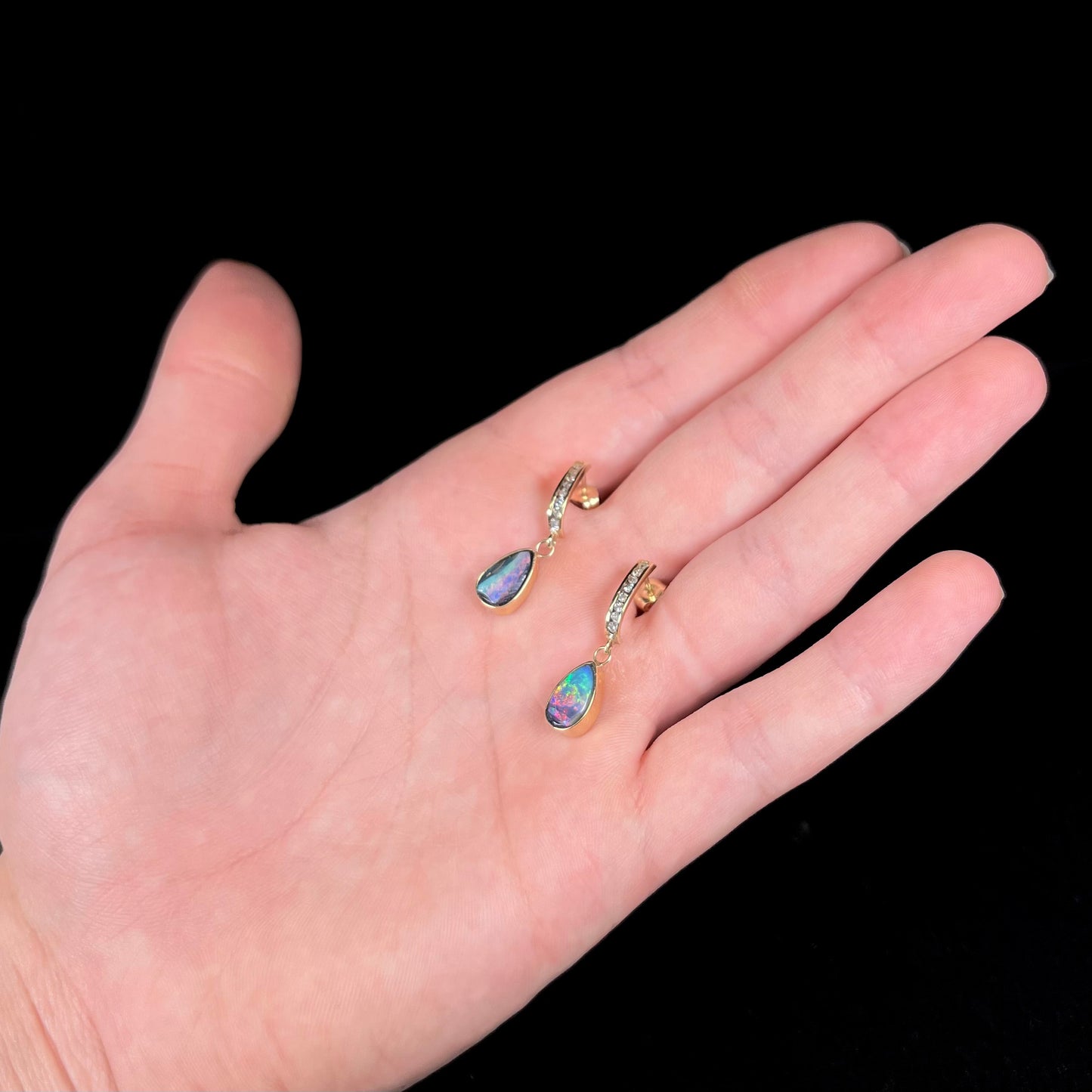 A pair of yellow gold dangle earrings set with natural pear shaped boulder opals and diamonds.