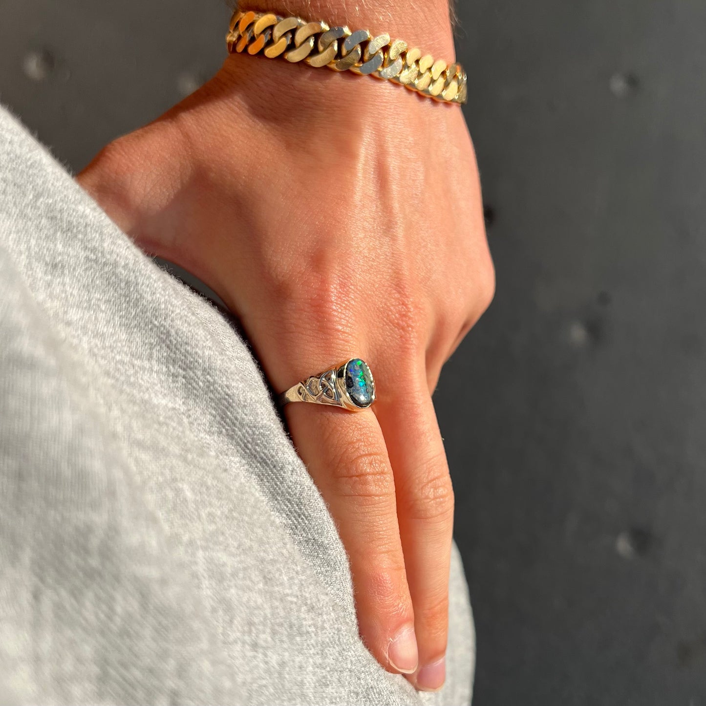 A unisex Celtic style natural boulder opal ring cast in yellow gold. The opal shines green and blue.