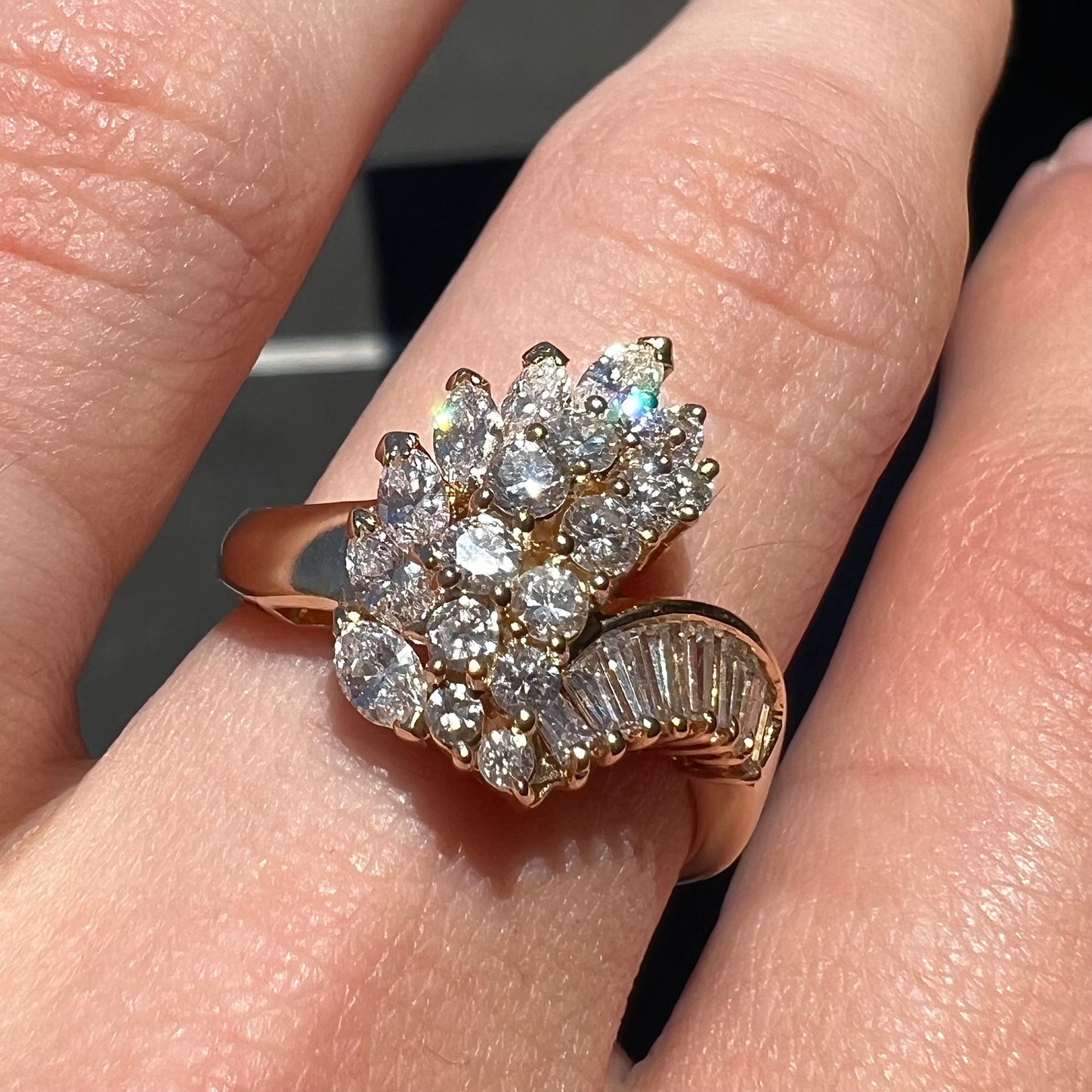 A yellow gold diamond cluster ring set with round, marquise, and baguette cut diamonds.