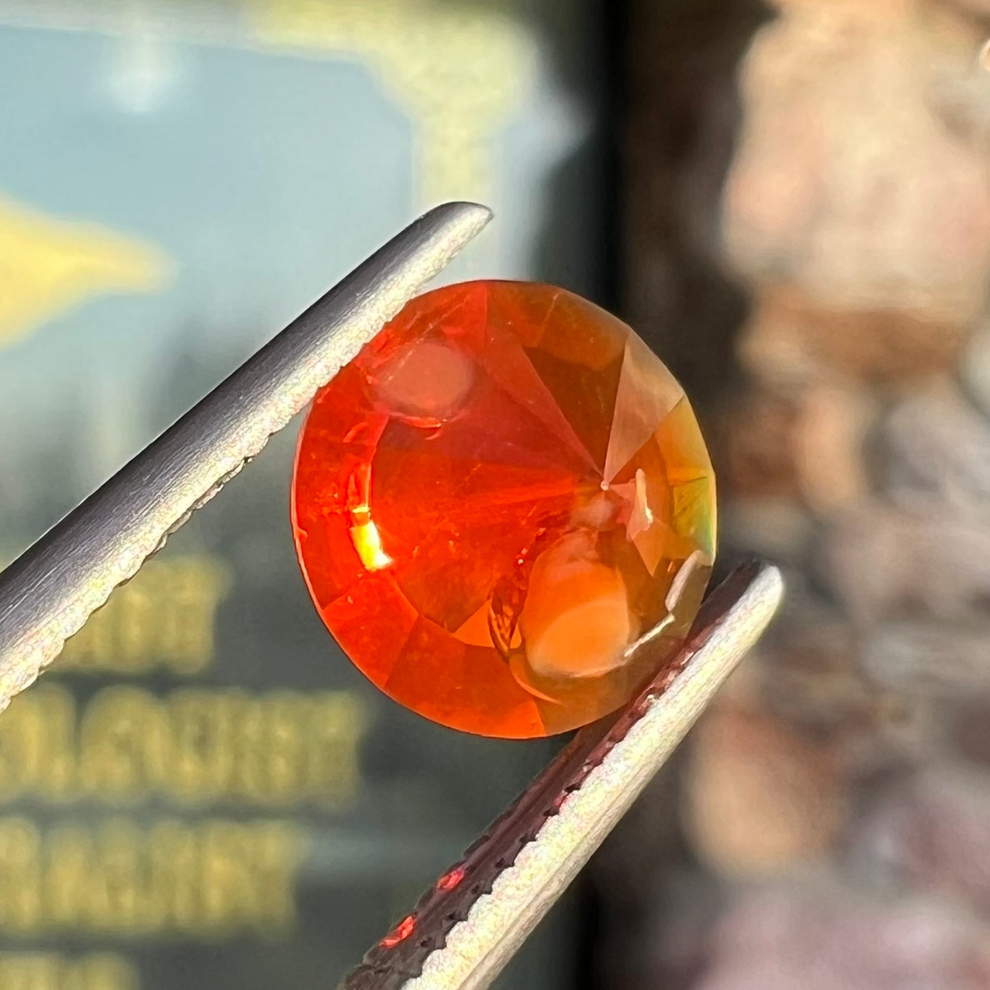A faceted round cut natural fire opal from Mexico. The stone is a bright orange color.