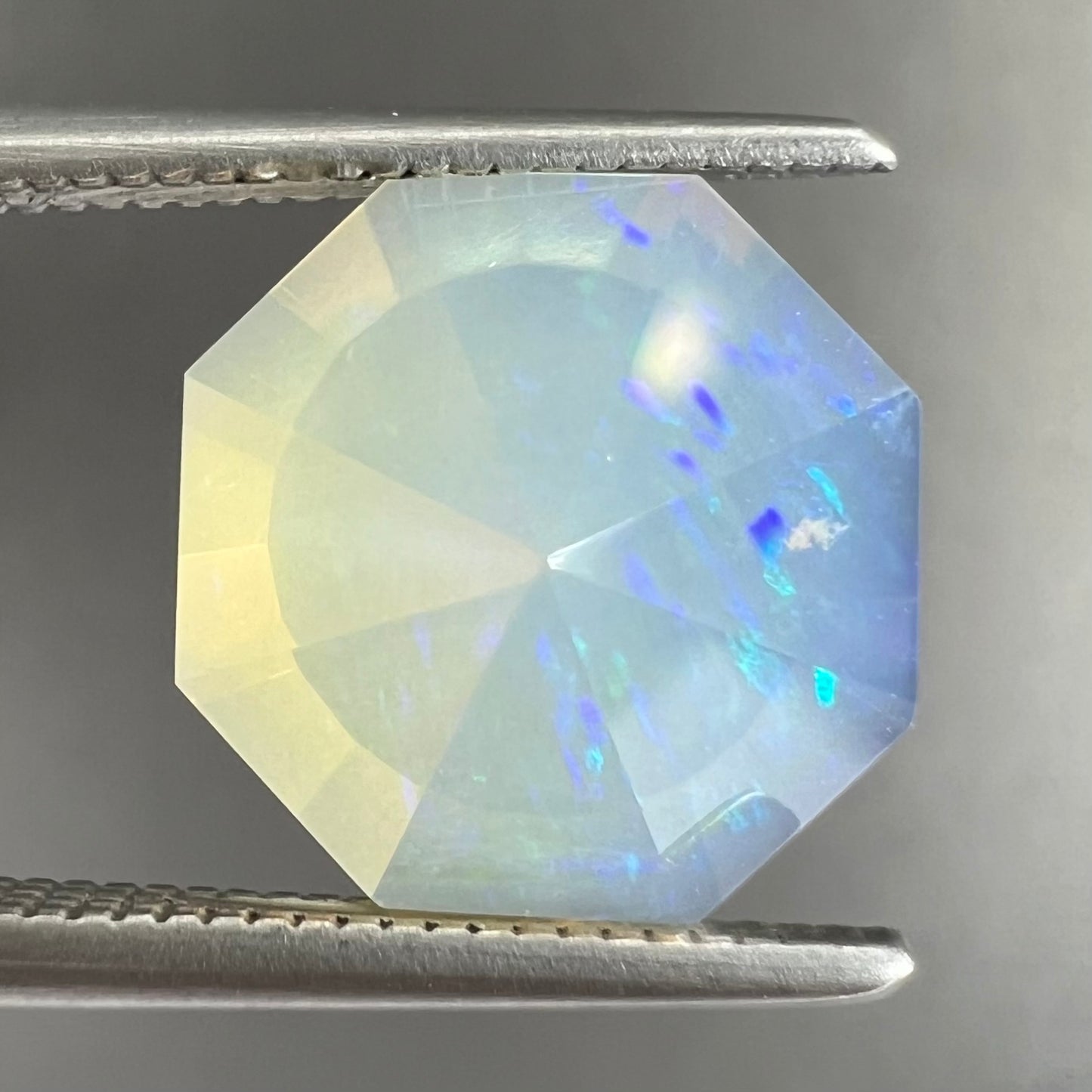 A loose, faceted octagon cut Mexican fire opal gemstone. The stone is a light yellow color with blue and green fire.