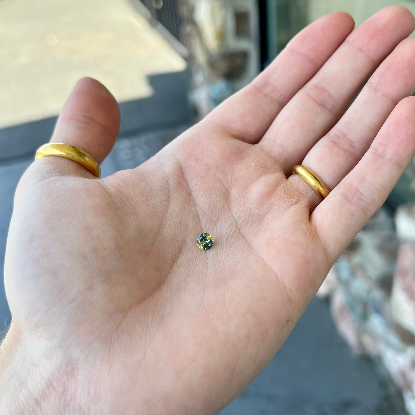 A loose, round brilliant cut Australian parti sapphire. The stone shows colors of yellow, green, and blue.