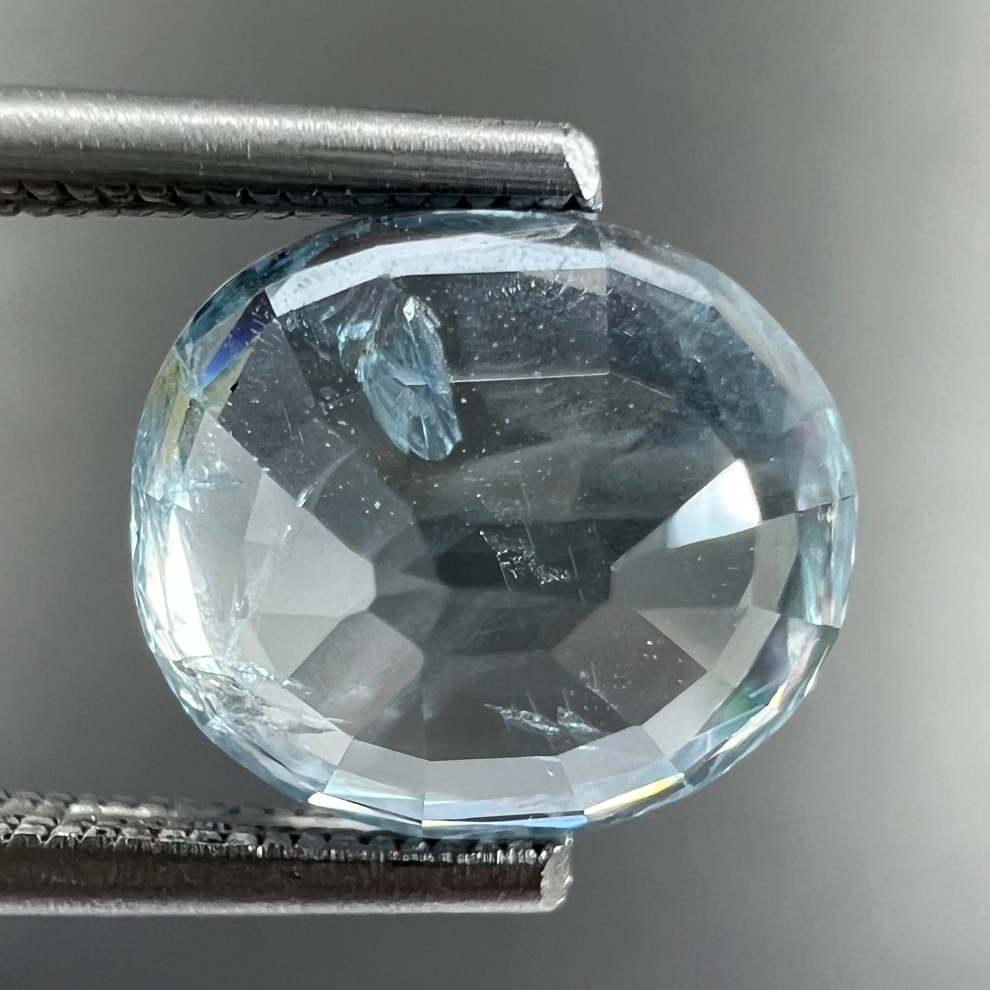 A loose, faceted oval cut light blue natural sapphire gemstone.