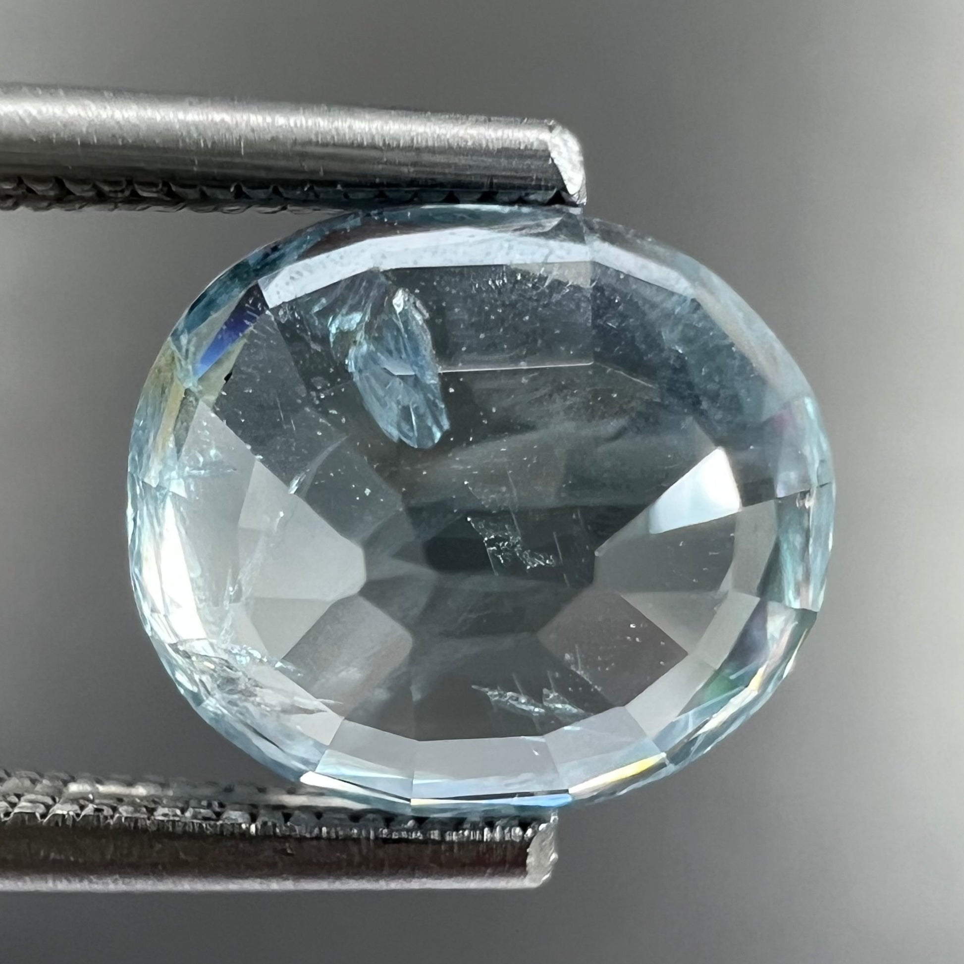 A loose, faceted oval cut light blue natural sapphire gemstone.