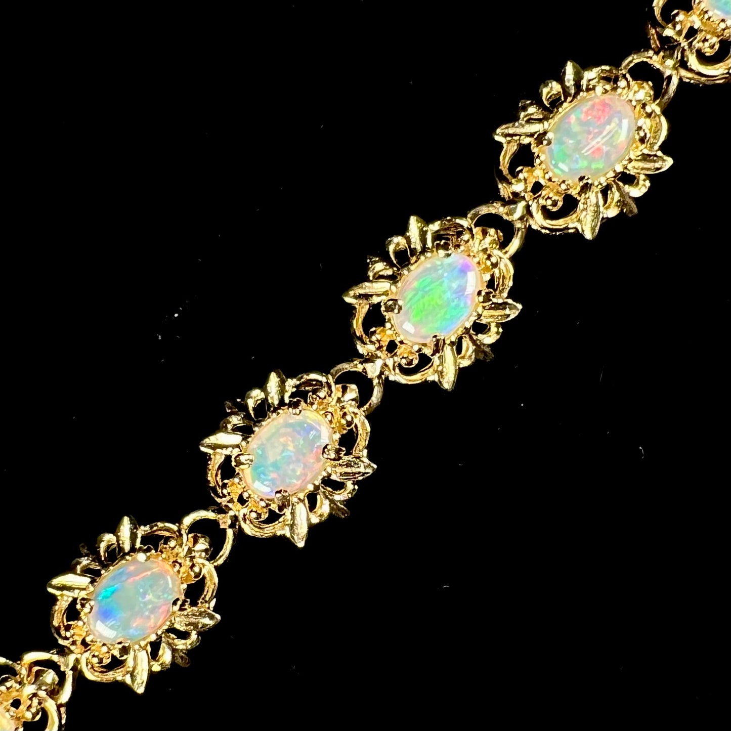 A ladies' yellow gold bracelet set with natural, oval cabochon cut white crystal opals.