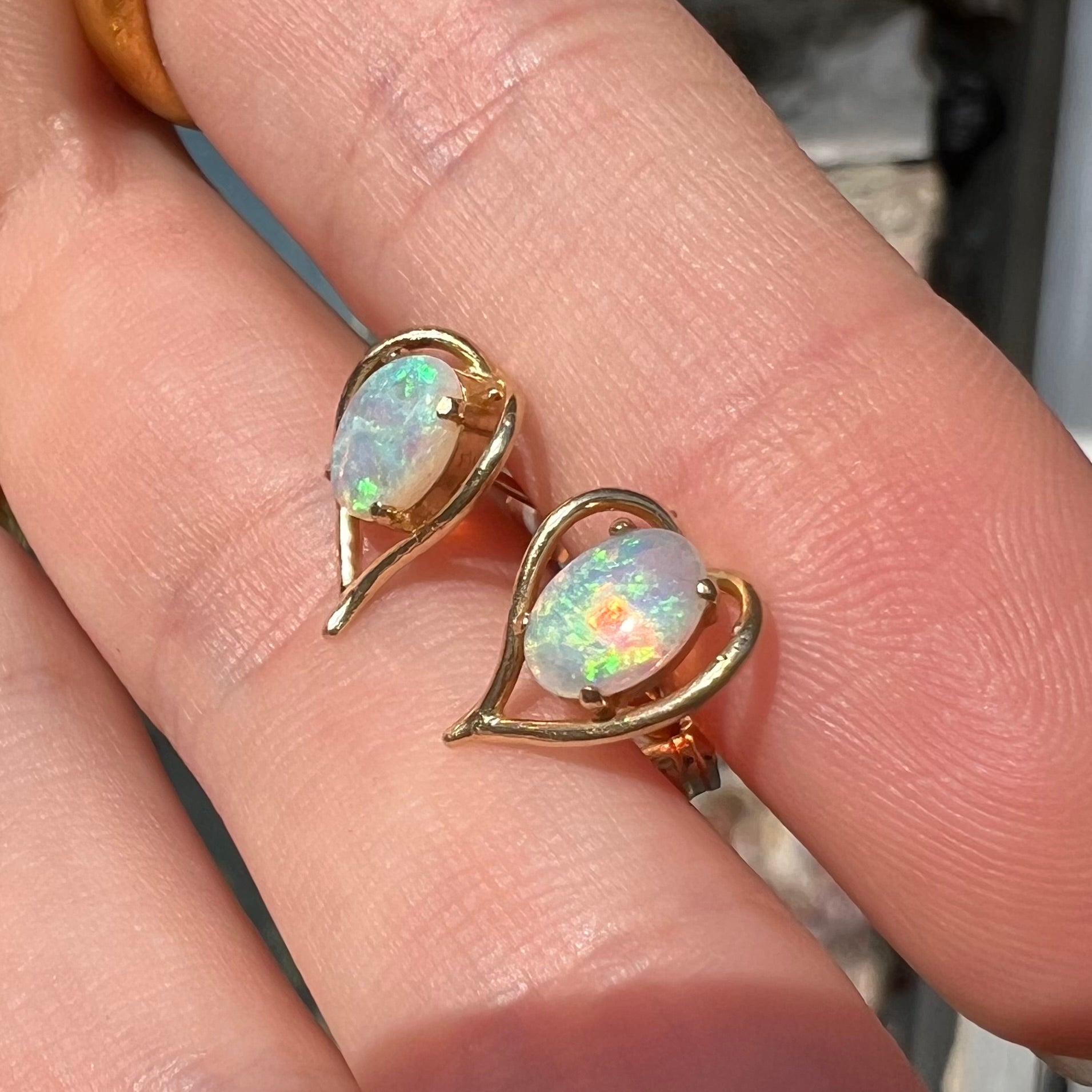 A pair of yellow gold, heart shaped stud earrings set with oval cabochon cut natural opal stones.
