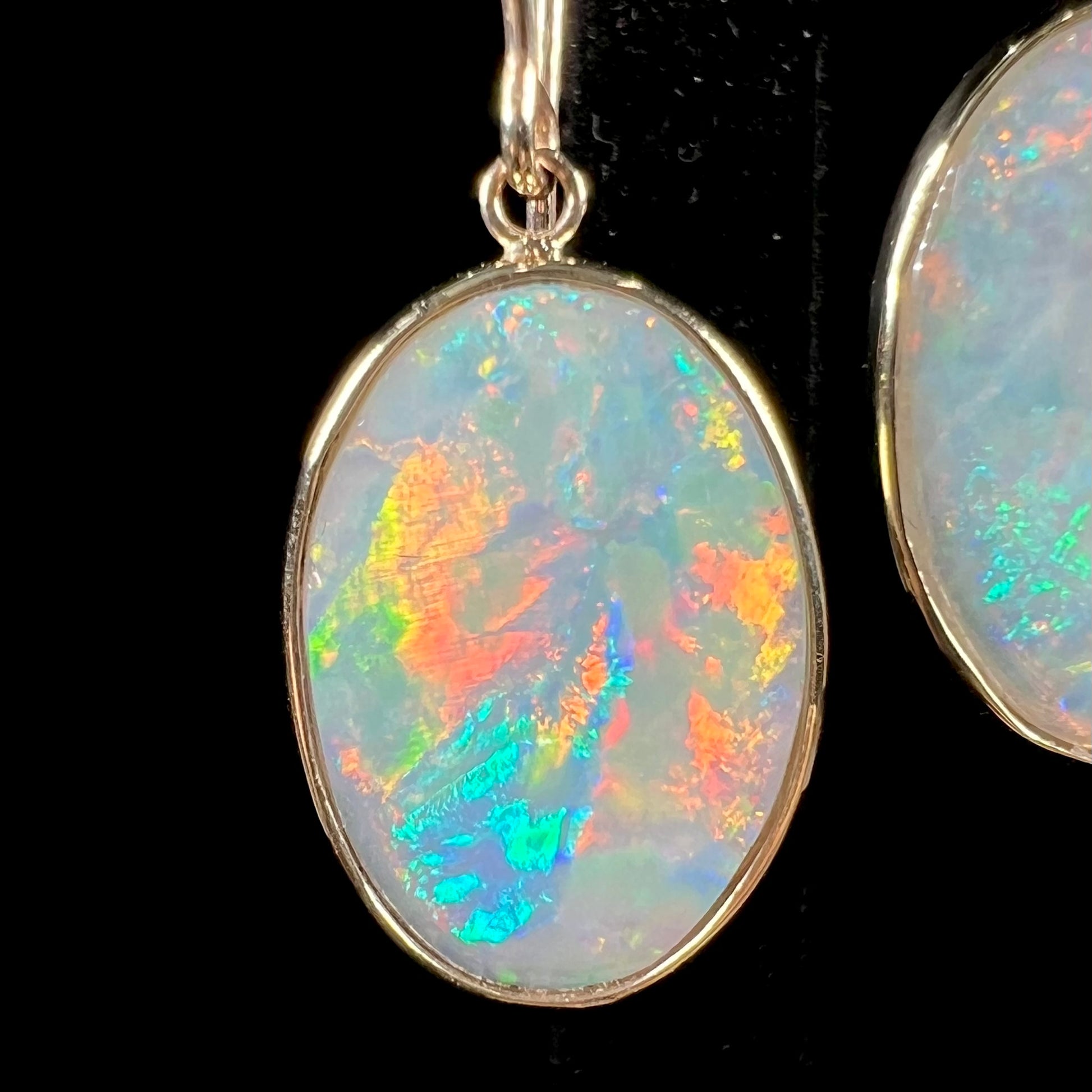 A pair of yellow gold earrings bezel set with oval cabochon cut natural opal stones.