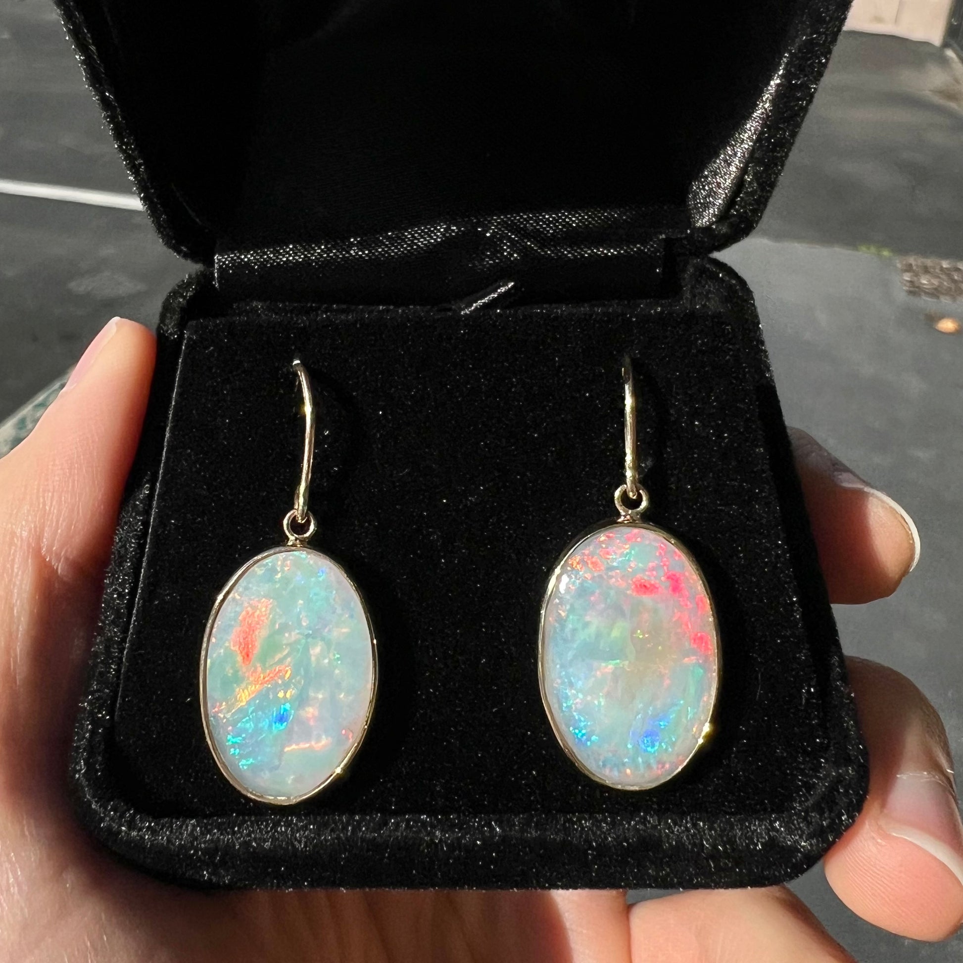 A pair of yellow gold earrings bezel set with oval cabochon cut natural opal stones.