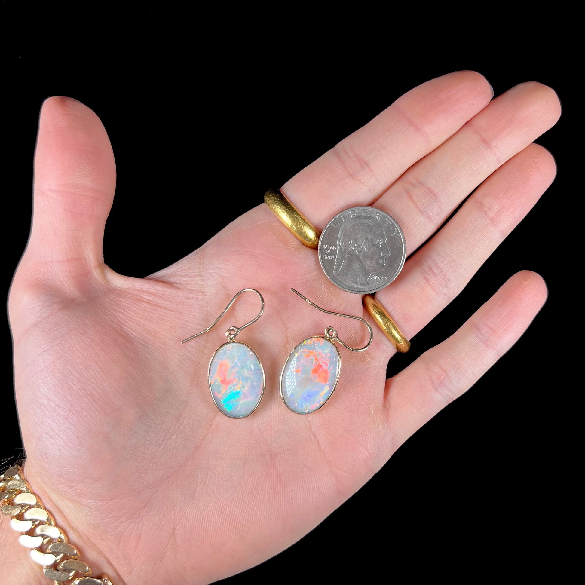 A pair of yellow gold earrings bezel set with oval cabochon cut natural opal stones.