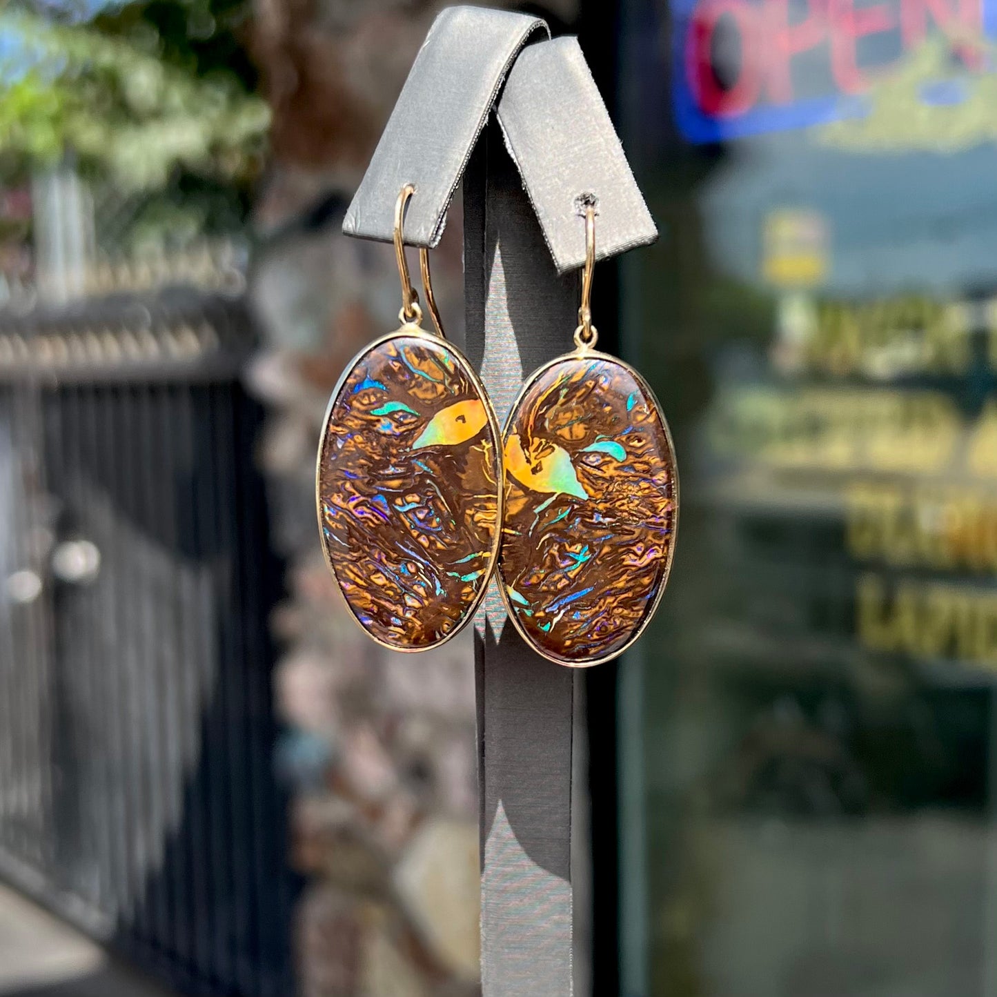 A pair of Koroit boulder opal dangle earrings set in yellow gold bezels.