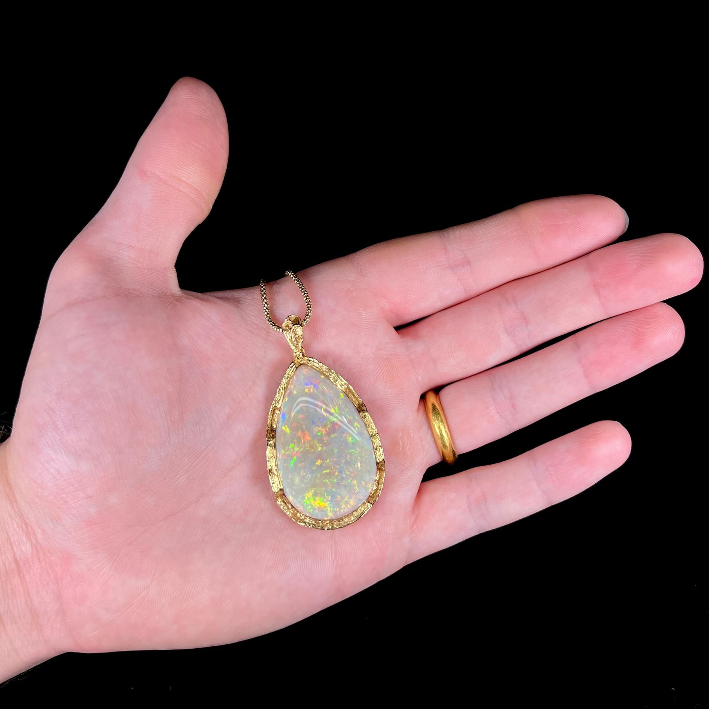 A ladies' natural, pear shaped, gray base Australian opal pendant set in 18 karat yellow gold.