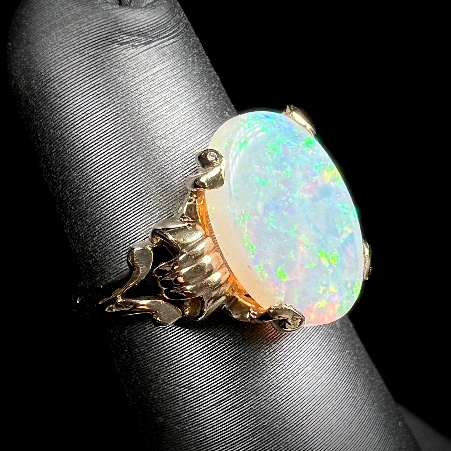A ladies' Art Deco style natural opal solitaire ring in yellow gold. The opal is oval cut.