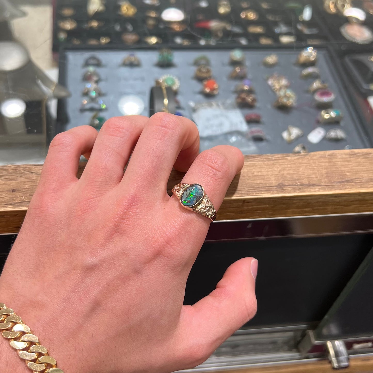 A unisex Celtic style natural boulder opal ring cast in yellow gold. The opal shines green and blue.