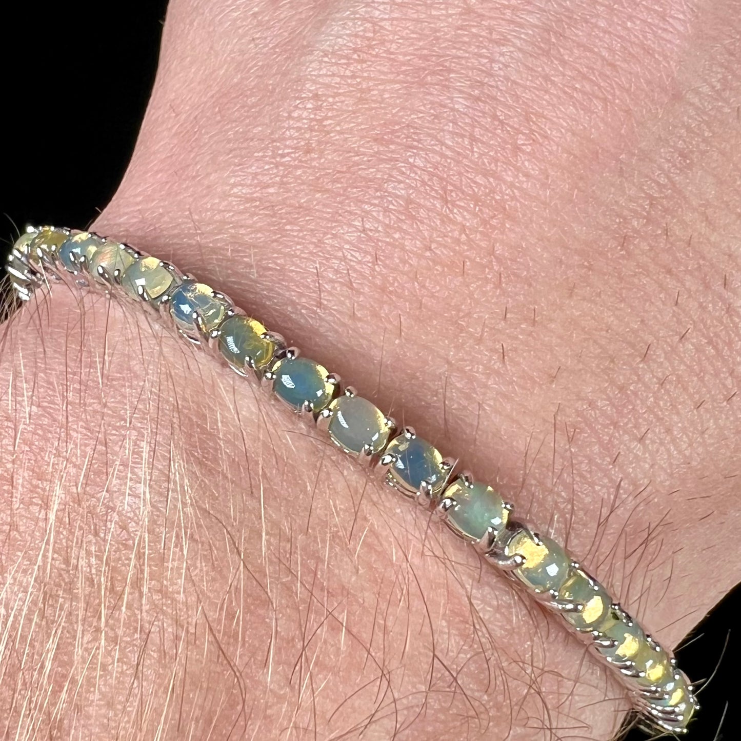 A ladies' sterling silver tennis style bracelet set with natural orange yellow Mexican fire opals.
