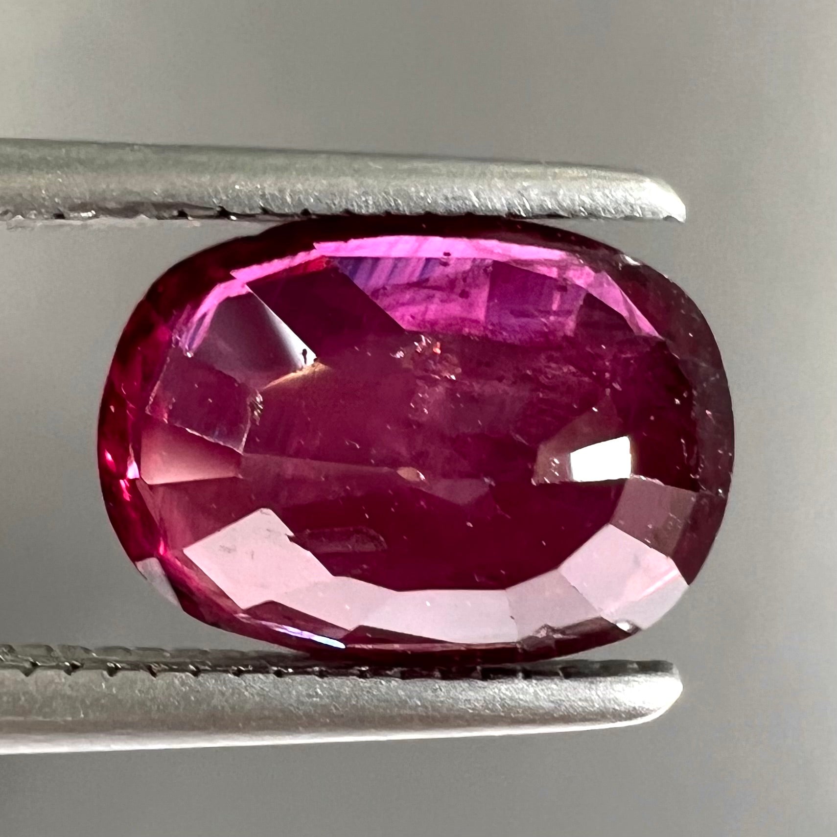 A loose, natural purplish ruby gemstone.  There is a small, minute chip on the girdle of the gem.