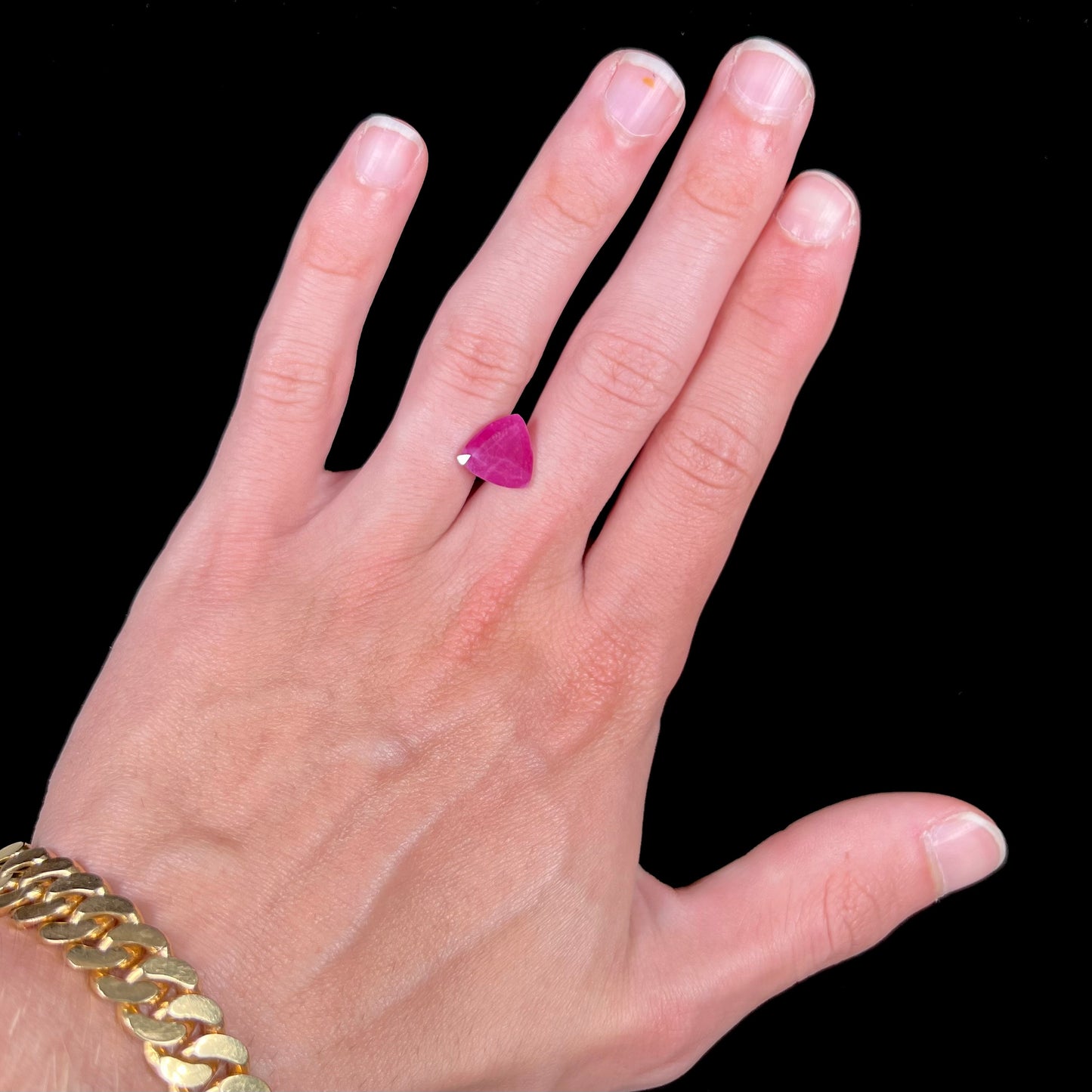 A loose, faceted trillion cut, natural, commercial grade ruby gemstone. The stone is purplish red color.